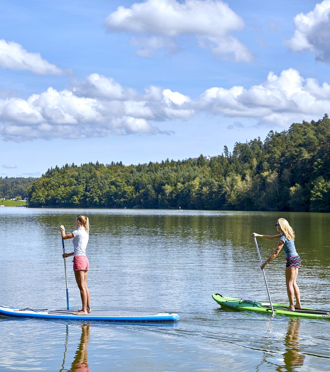 Zwei Frauen beim Stand Up Paddling auf einem See