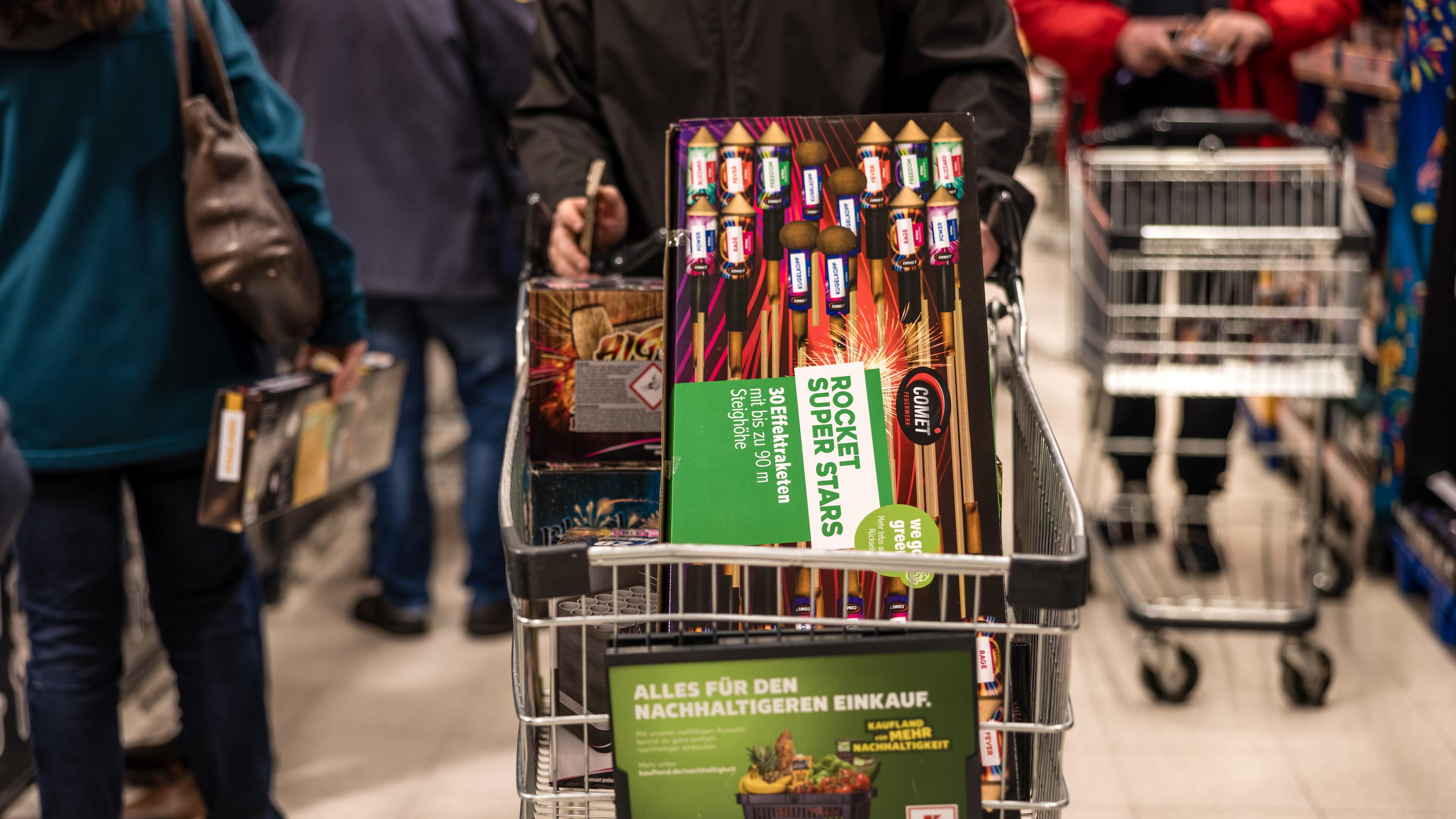 Ein Kunde fährt mit einem Einkaufswagen voller Feuerwerk durch einen Supermarkt.