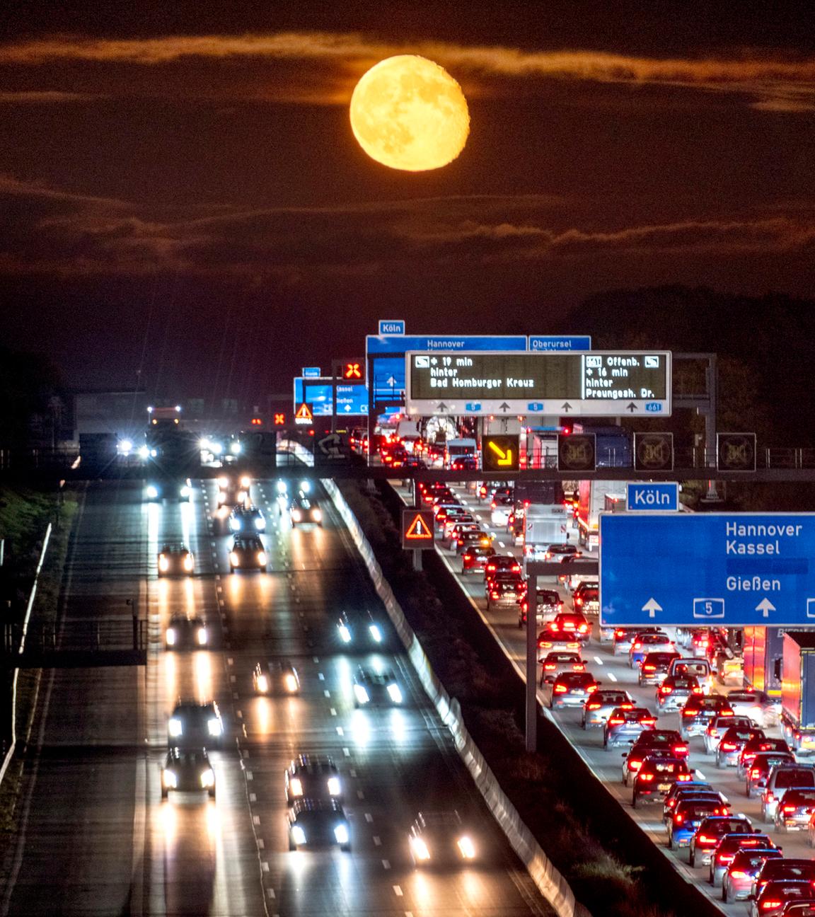 Symbolbild: Autos und Lastwagen stehen auf einer Autobahn bei Frankfurt im Stau, während der Mond aufgeht. 