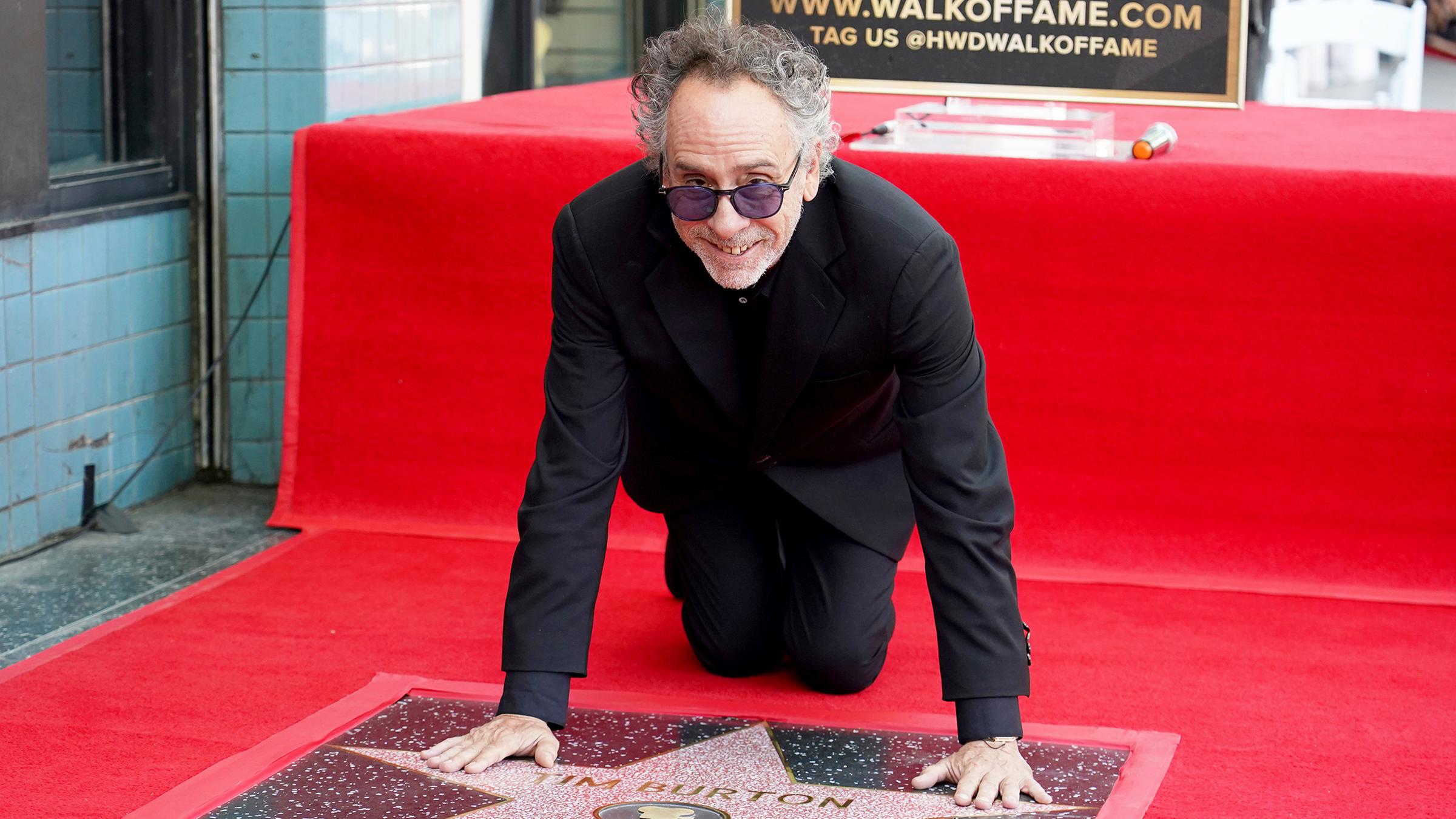 Der Regisseur Tim Burton stützt sich auf seinen Stern beim Hollywood Walk of Fame.