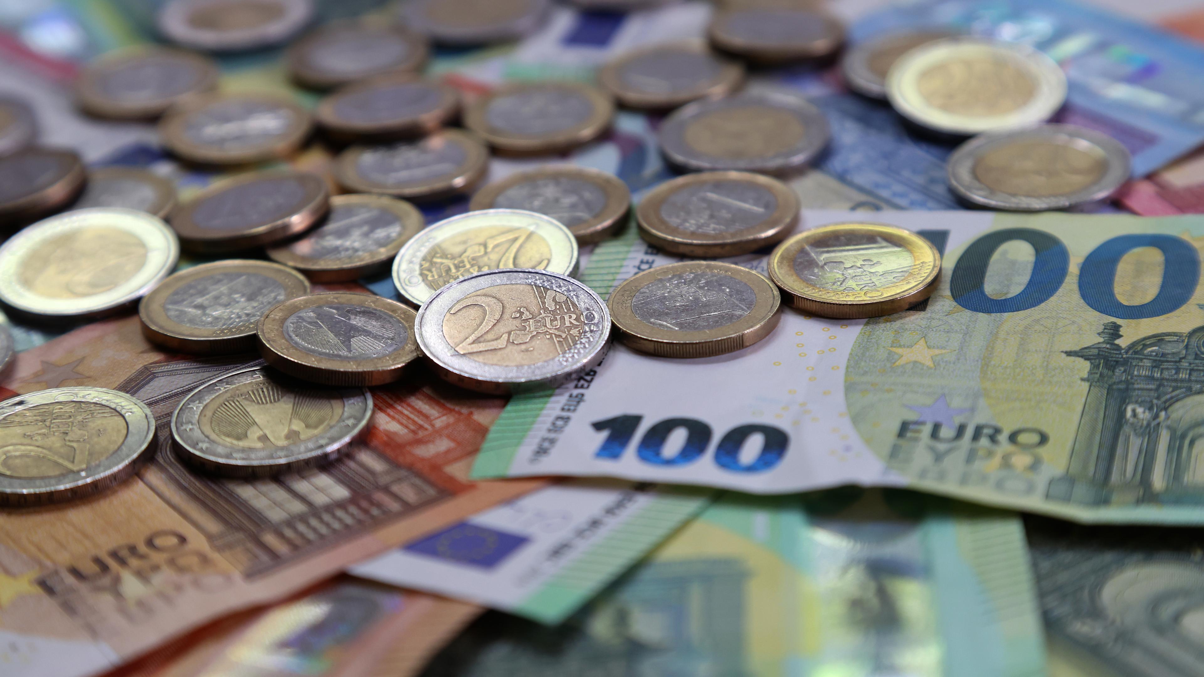Verschiedene Euro-Banknoten und Euro-Münzen liegen auf einem Tisch
