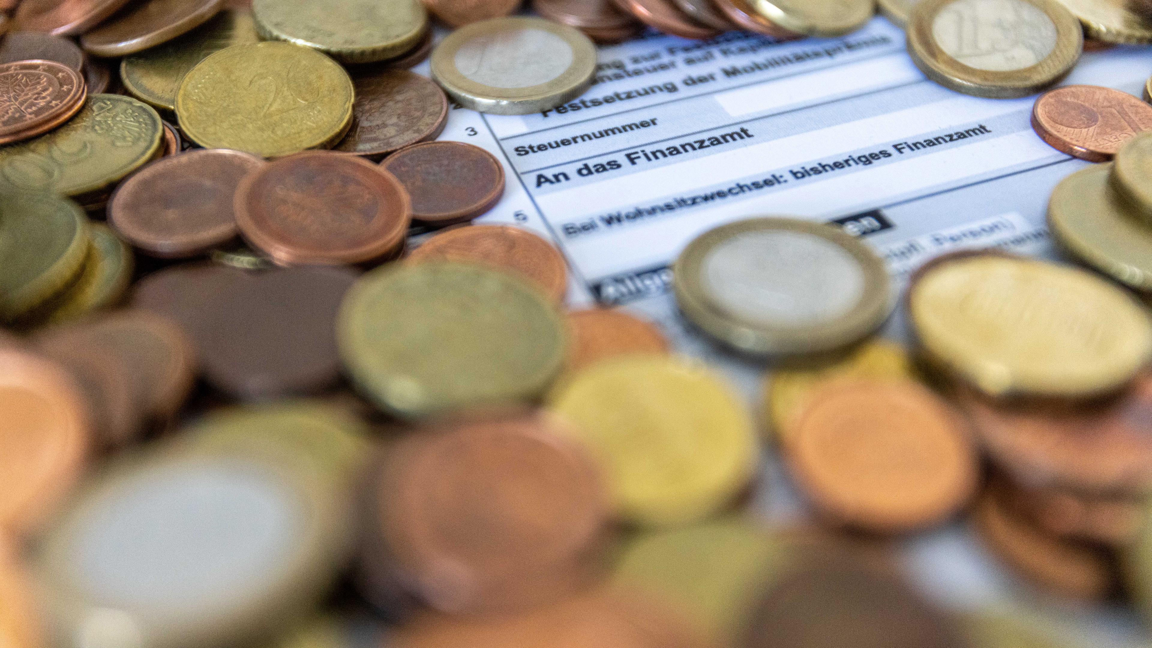 Baden-Württemberg, Freiburg: Ein Formular zur Steuererklärung ist von Euro-Münzen bedeckt. 