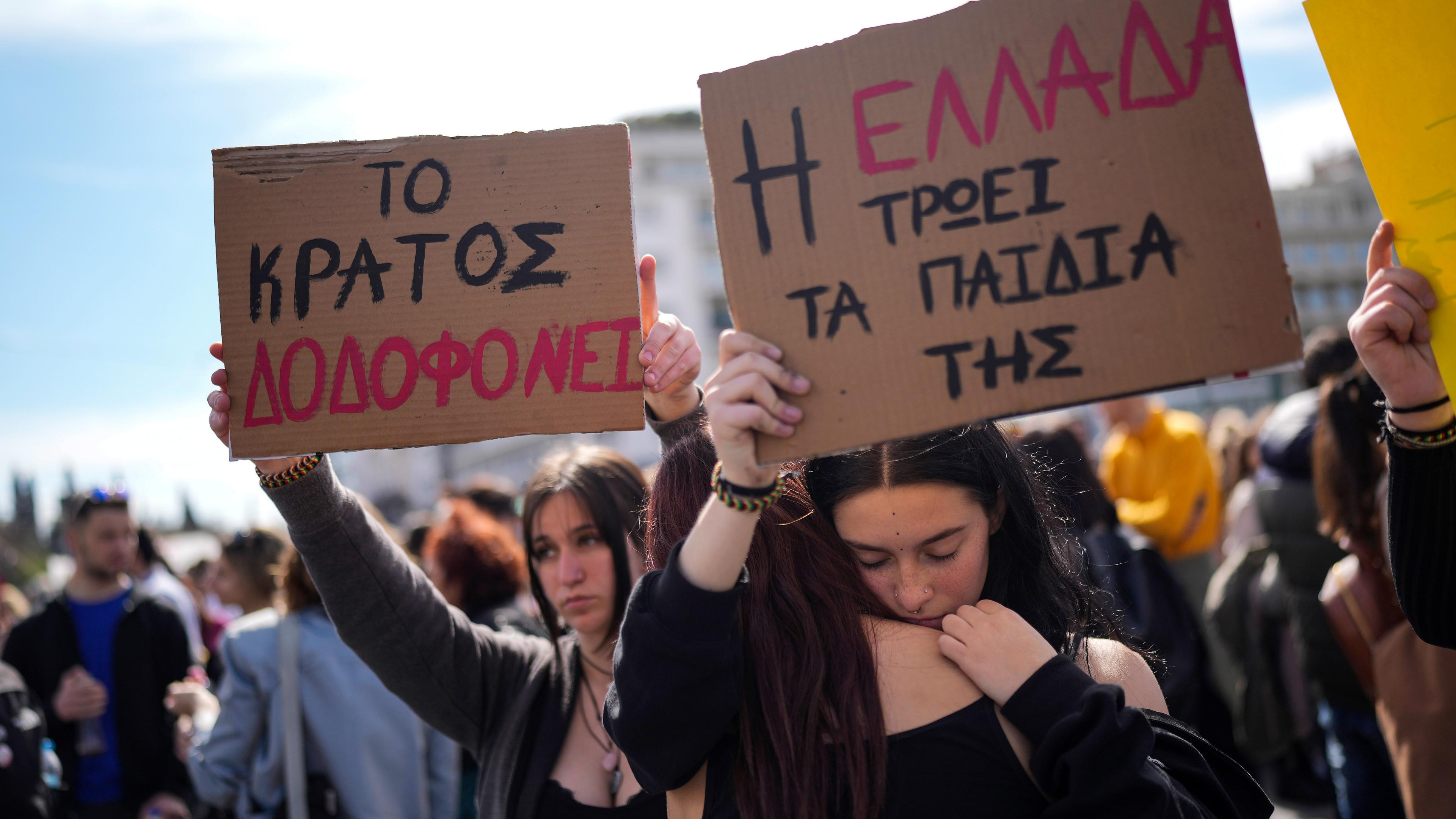 Demonstranten halten Plakate mit der Aufschrift «Griechenland frisst seine Kinder» (r) und «Der Staat mordet», während eines Protests für die Opfer eines Zugunglücks