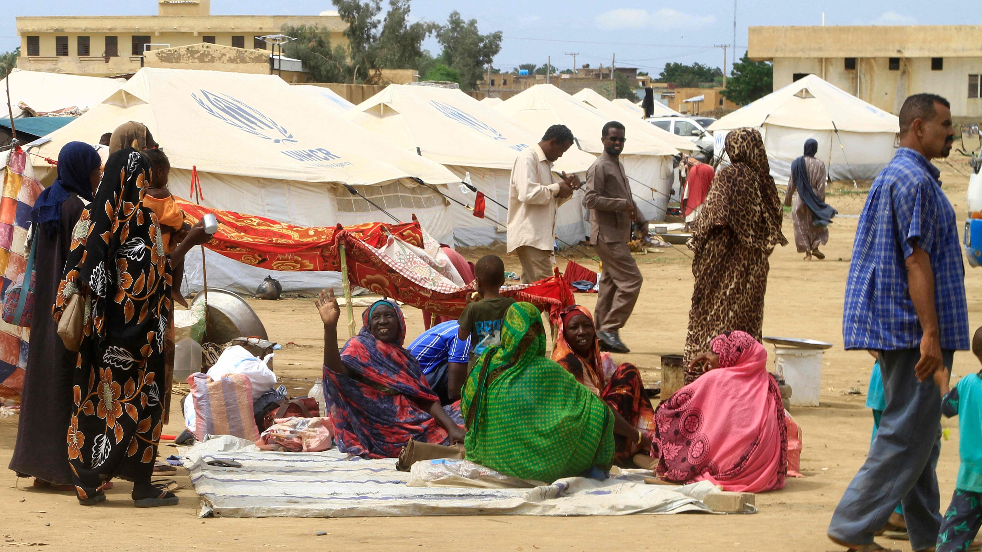 Sudanesen, die bereits durch den Konflikt vertrieben wurden, gehen in der Nähe von Zelten auf einem provisorischen Lagerplatz, zu dem sie nach tödlichen Überschwemmungen in der ostsudanesischen Stadt Kassala am 12. August 2024 evakuiert wurden