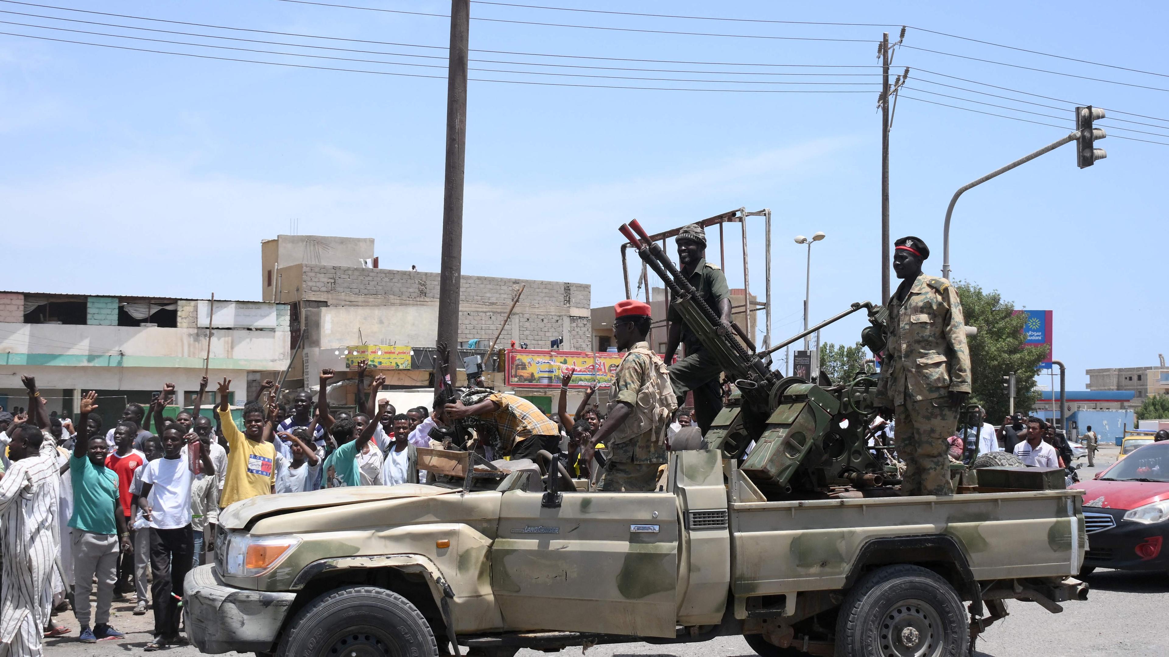 Ein Auto der sudanischen Armee fährt an Zivilisten vorbei. 