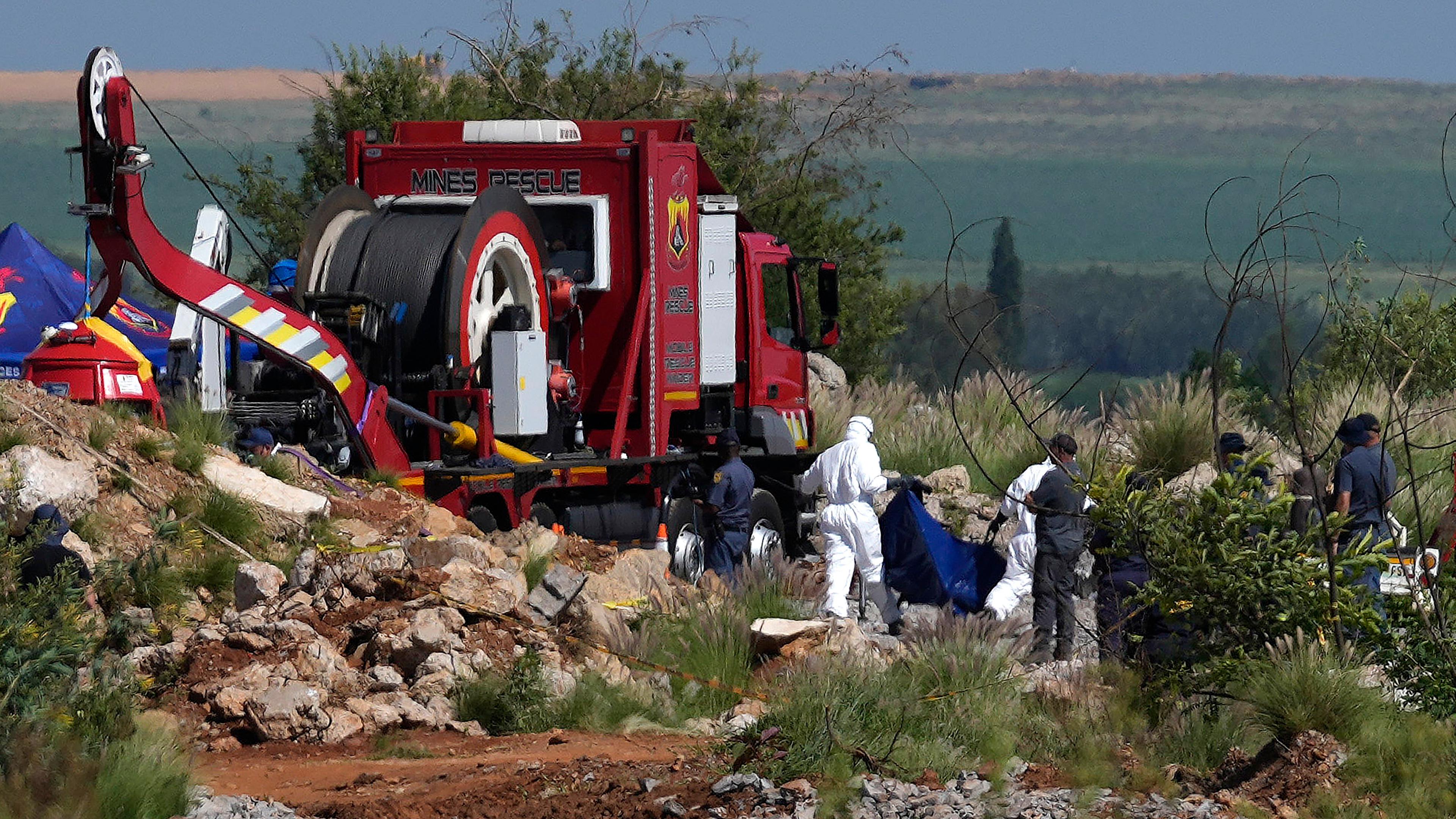 Forensic service workers carry remains in blue body bags during a rescue operation to rescue miners from below ground in an abandoned gold mine in Stilfontein, South Africa