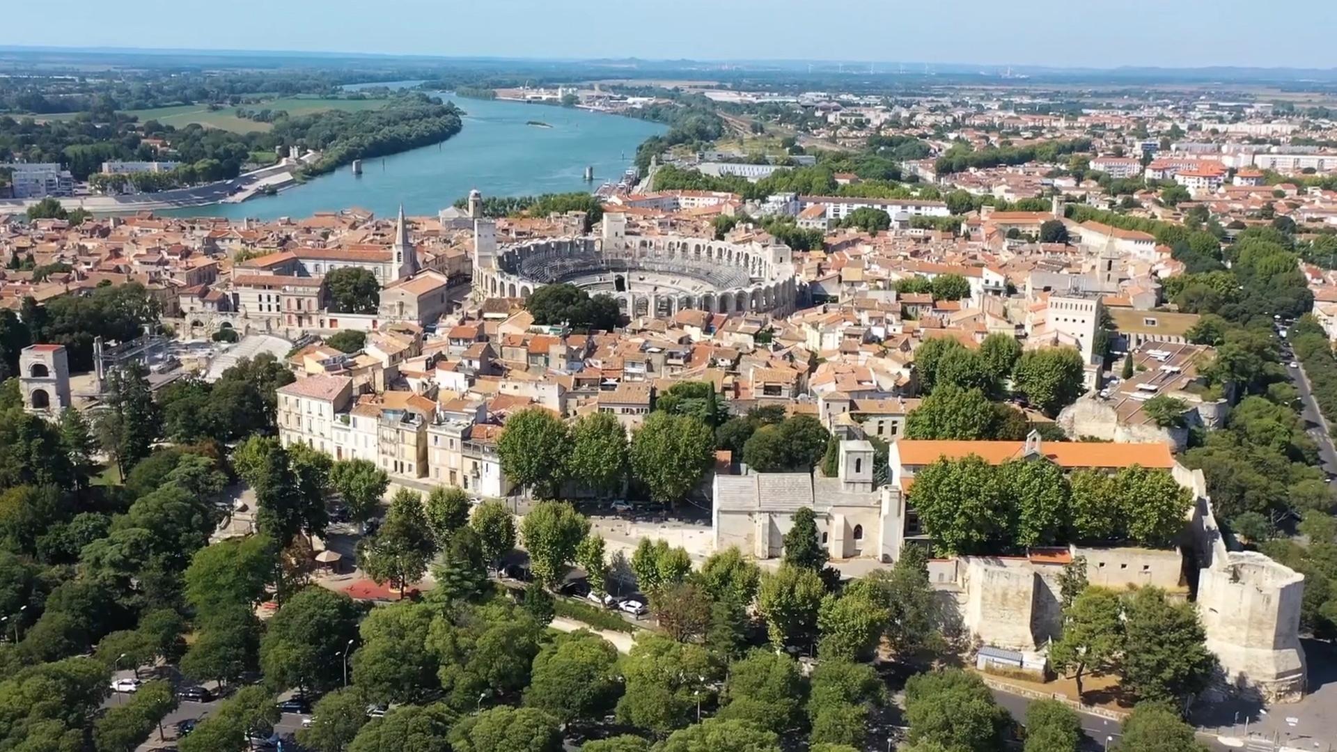 Blick von schräg oben auf das Amphitheater in Arles und auf die Rhone, die an der Stadt vorbeifließt.