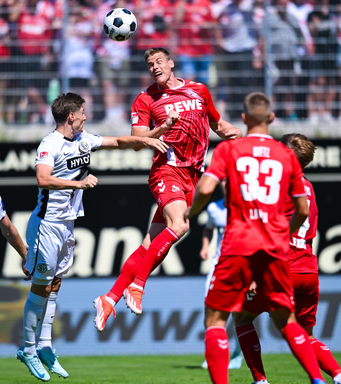  Steffen Tigges von Köln (oben, r) und Carlo Sickinger von Elversberg im Kopfballduell. 