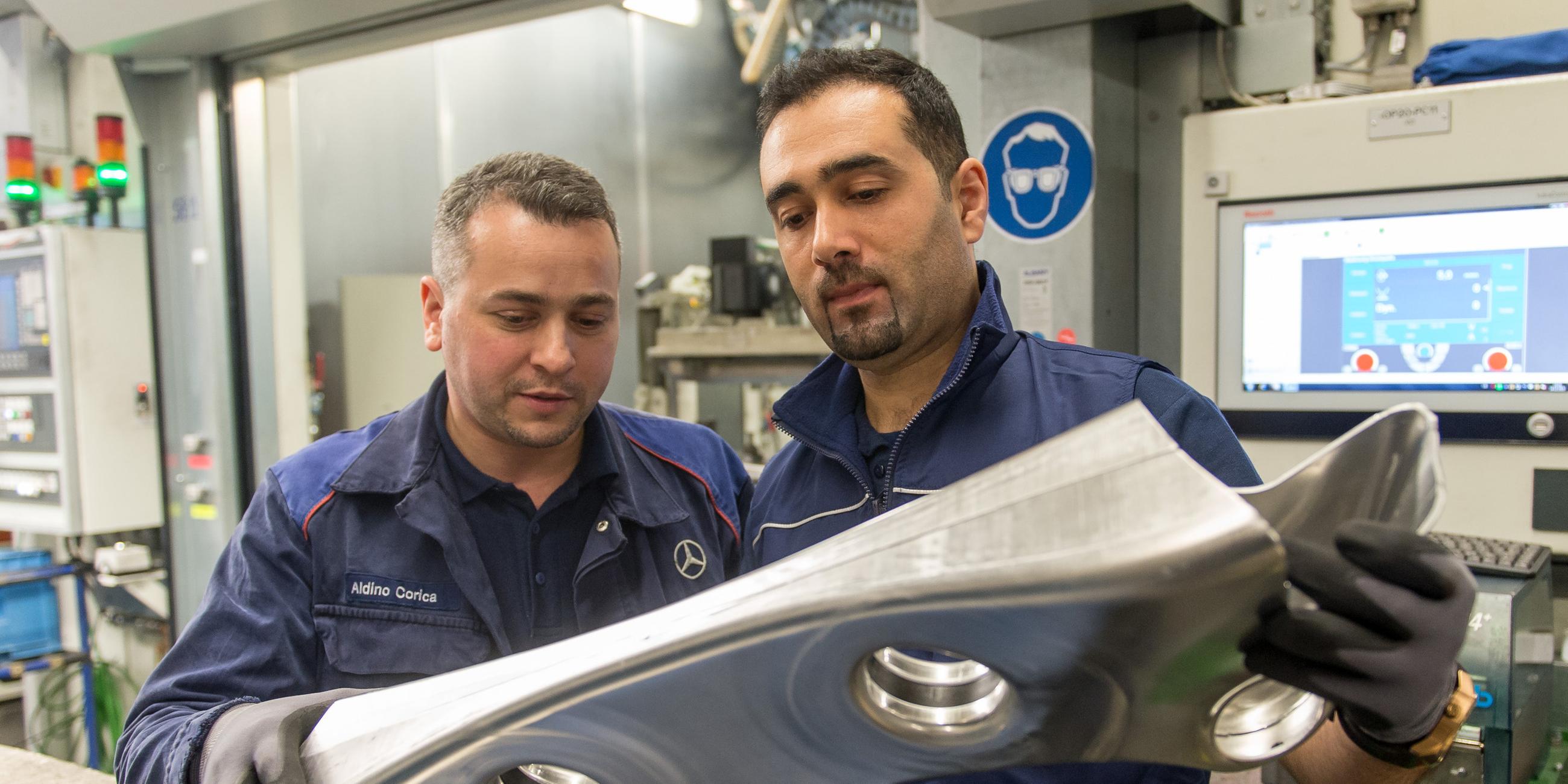 Der aus Syrien stammende Flüchtling Mohammed K. (r) überprüft am 14.12.2015 in der Daimler-Gießerei in Esslingen-Mettingen (Baden-Württemberg) einen Achsträger zusammen mit seinem Paten Aldino Corcia. 