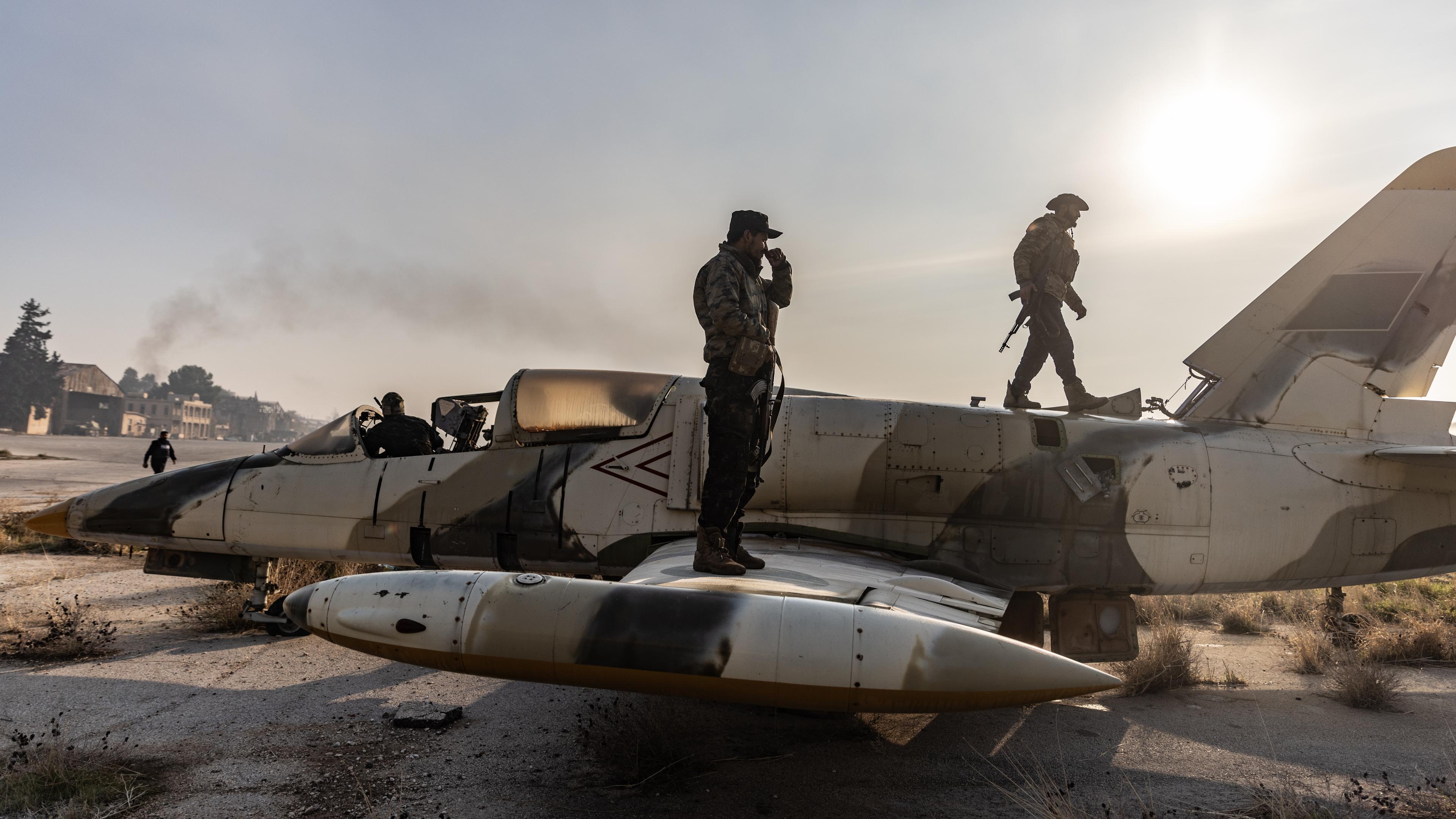 Mitglieder der bewaffneten syrischen Opposition stehen auf einem Militärflugzeug, nachdem sie die Kontrolle über den Militärflughafen Nayrab in der Stadt Aleppo übernommen haben.