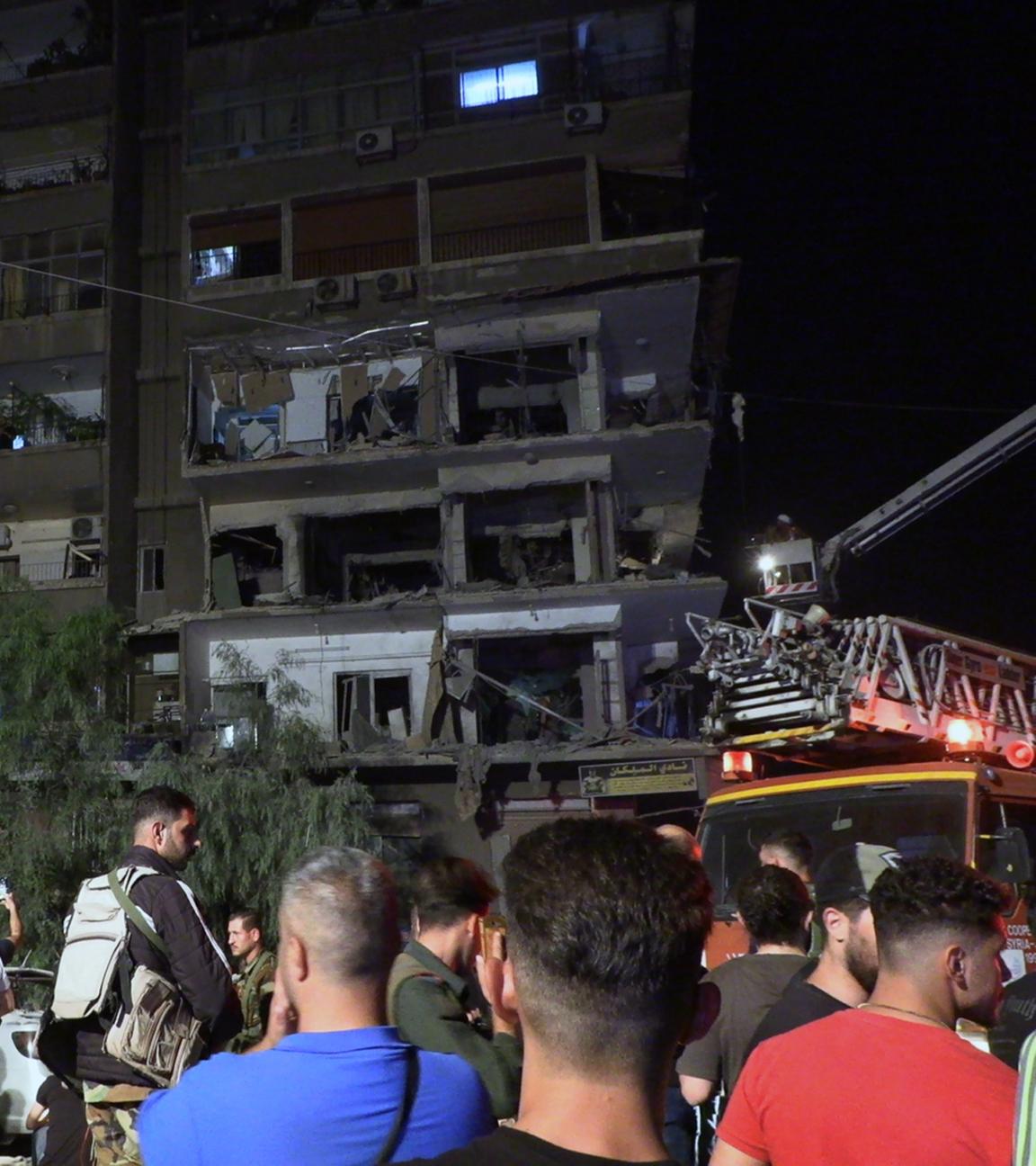 Syrische Soldaten und Menschen begutachten die Schäden nach dem Einschlag von Raketen auf das Gebäude im Viertel Al-Mazzeh in Damaskus