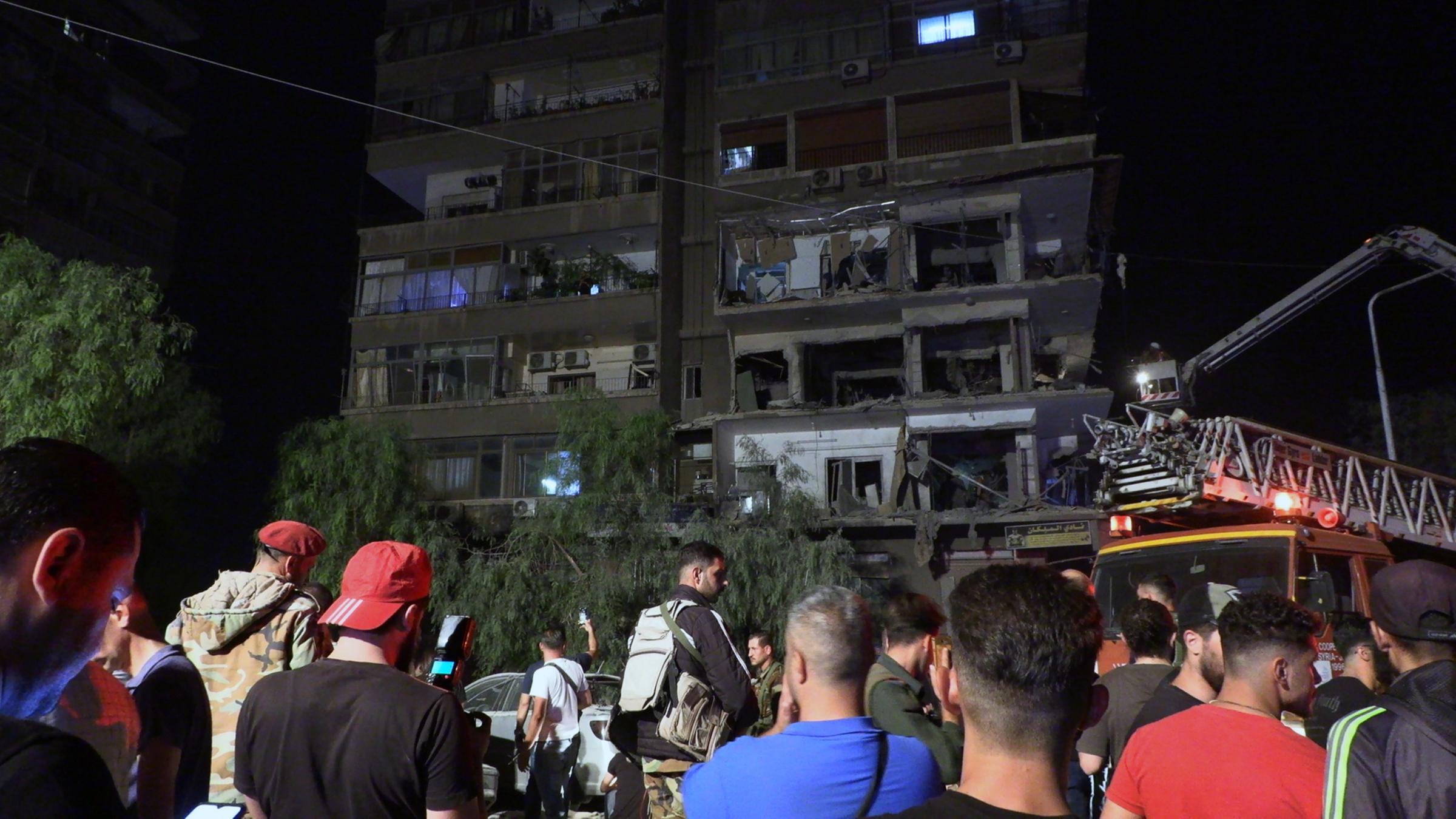 Syrische Soldaten und Menschen begutachten die Schäden nach dem Einschlag von Raketen auf das Gebäude im Viertel Al-Mazzeh in Damaskus