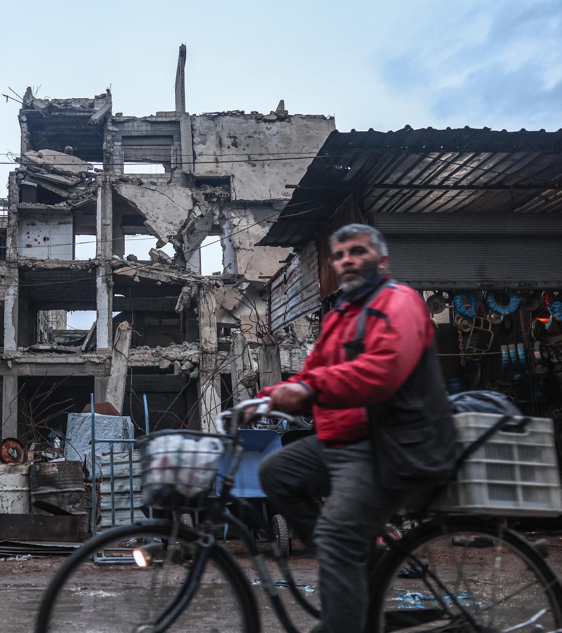 Ein Mann radelt an einem Gebäude vorbei, das durch Luftangriffe während der Assad-Herrschaft in Douma, am Stadtrand von Damaskus, beschädigt wurde.