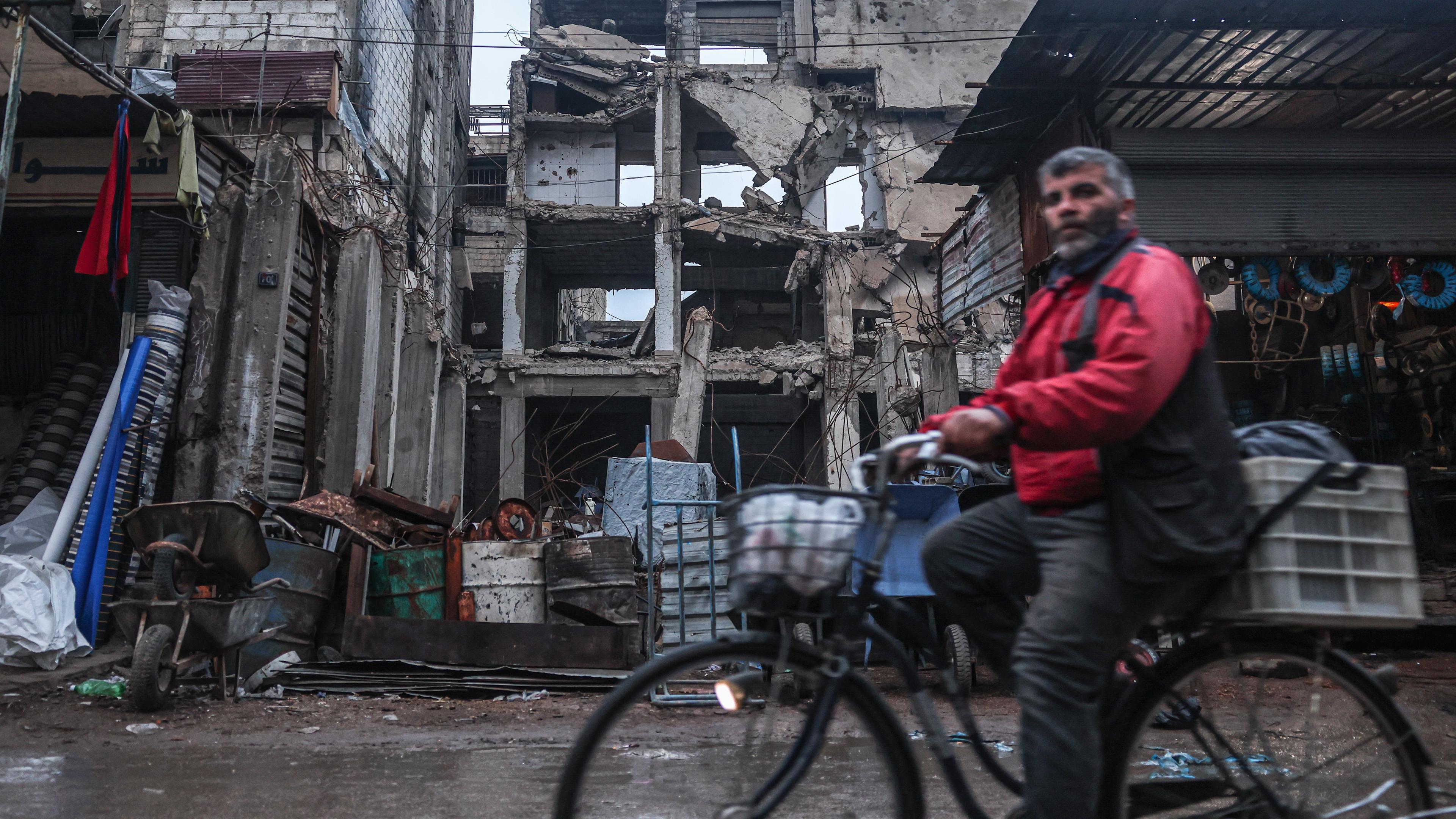 Ein Mann radelt an einem Gebäude vorbei, das durch Luftangriffe während der Assad-Herrschaft in Douma, am Stadtrand von Damaskus, beschädigt wurde.