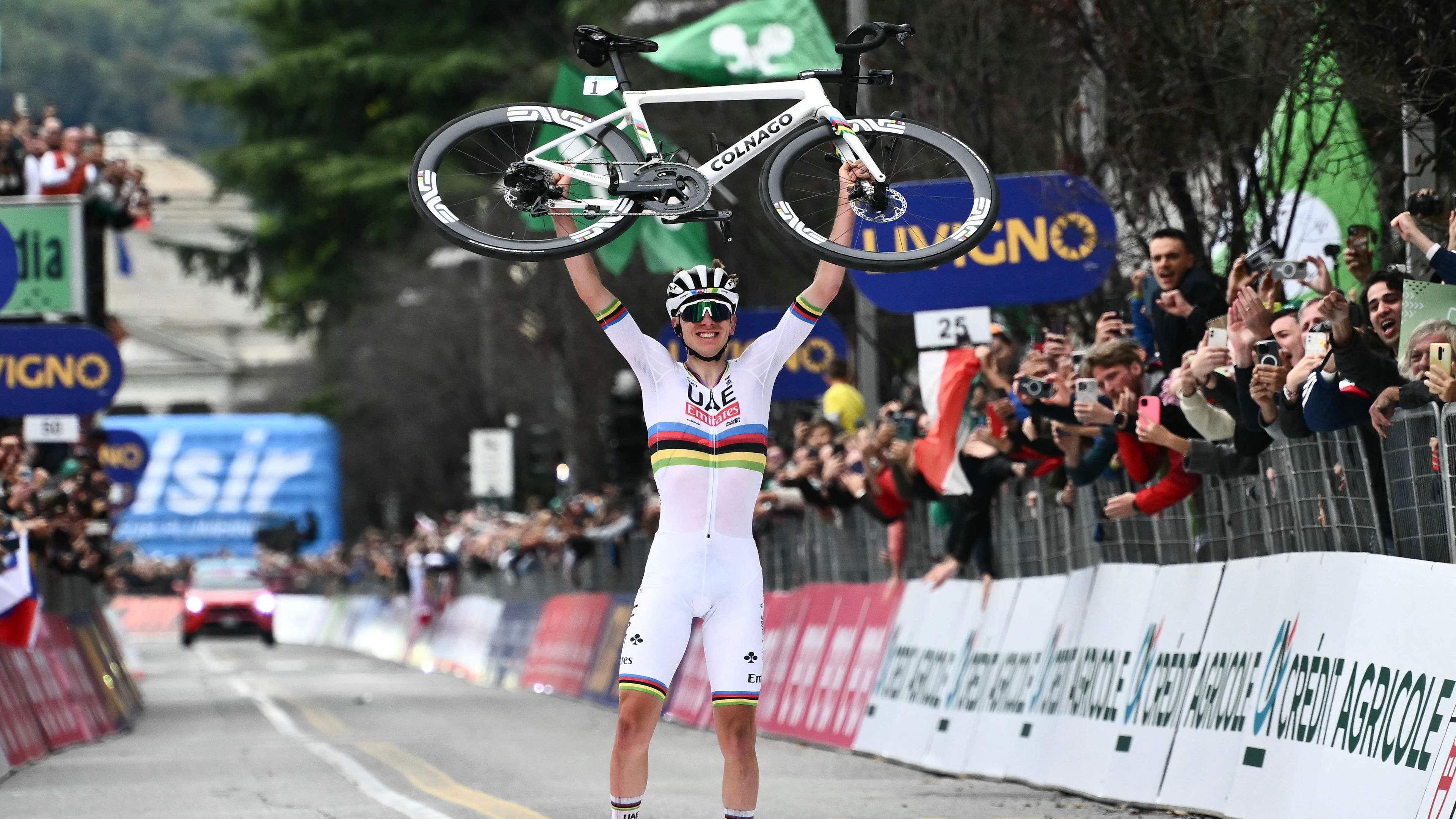 Der slowenische Fahrer Tadej Pogacar vom UAE Team Emirates hebt sein Fahrrad, nachdem er die Ziellinie überquert hat.