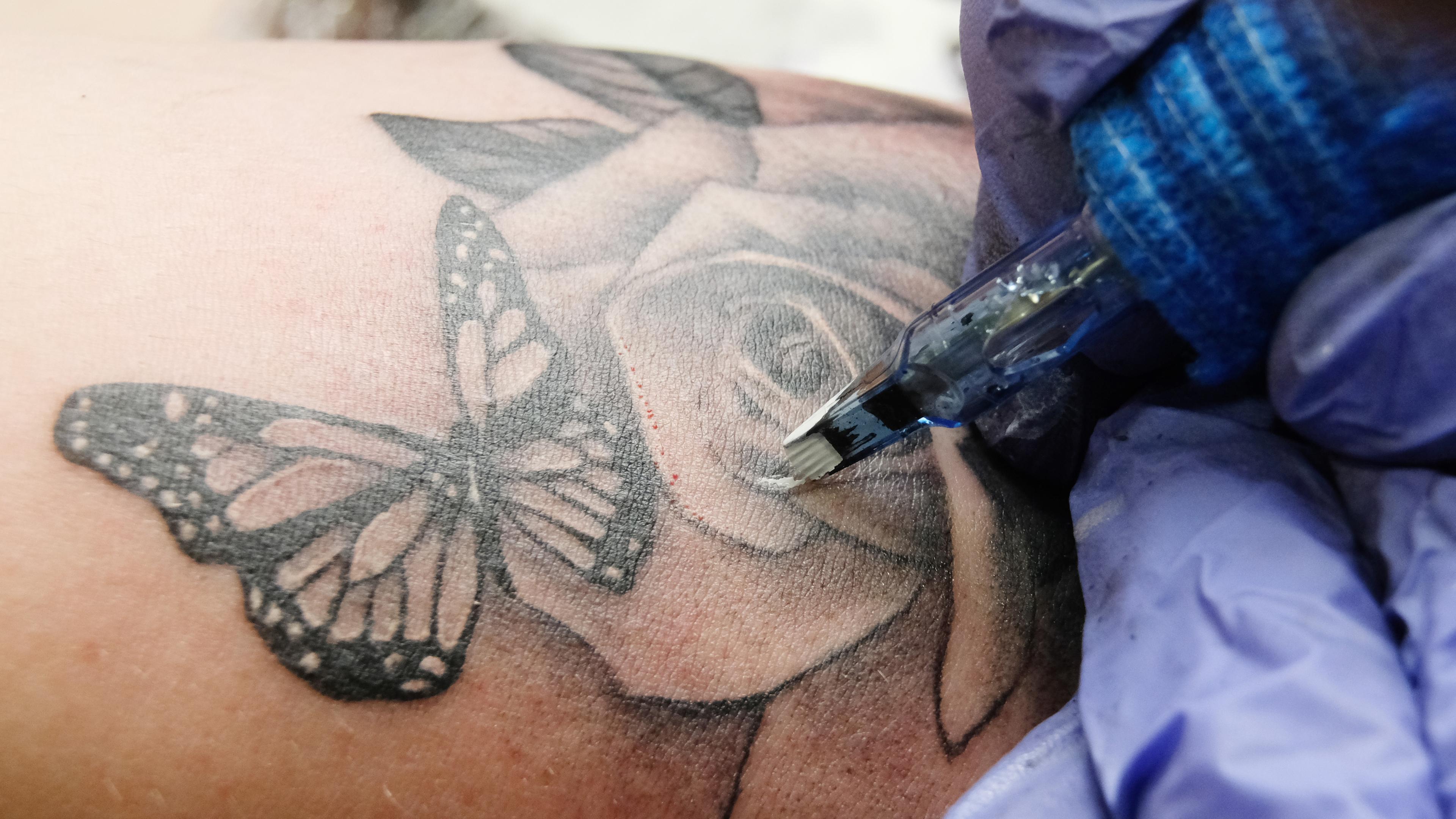 Eine Tätowierung in Form eines Schmetterlings wird während einer Tattoo-Messe auf einen Arm gestochen.