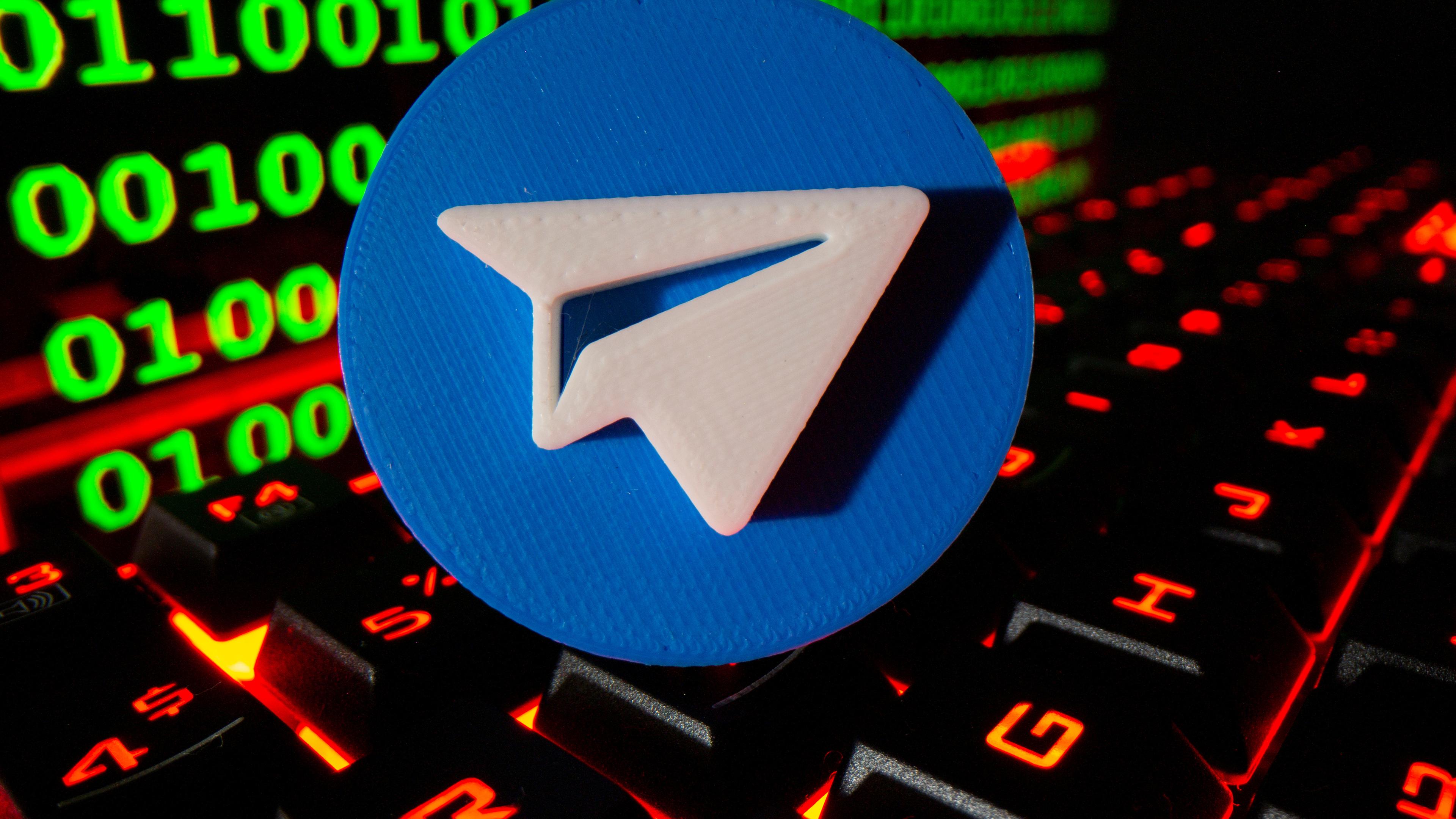 Ein 3D-gedrucktes Telegram-Logo ist auf einer Tastatur vor einem Binärcode abgebildet