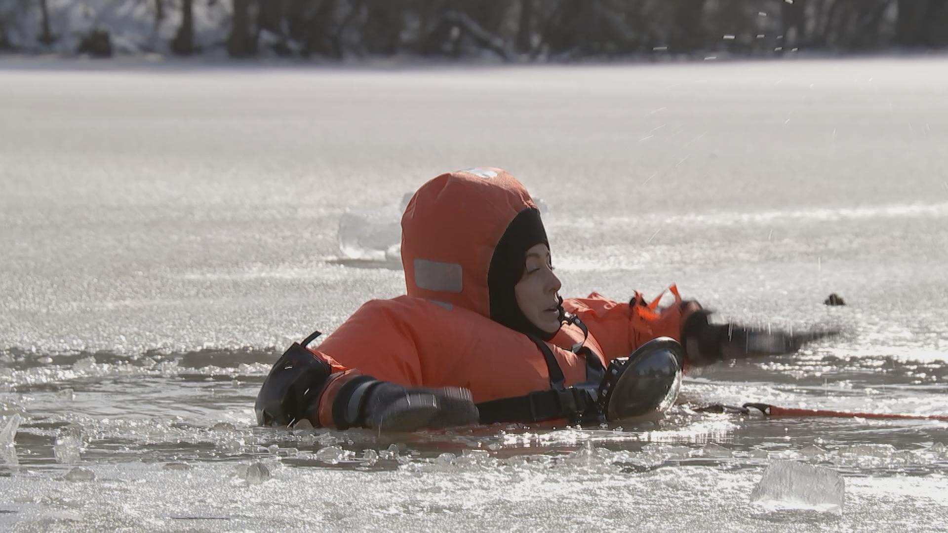 logo!-Reporterin Teresa schwimmt bei einer Übung mit einem dicken Schutzanzug in einem Eisloch.