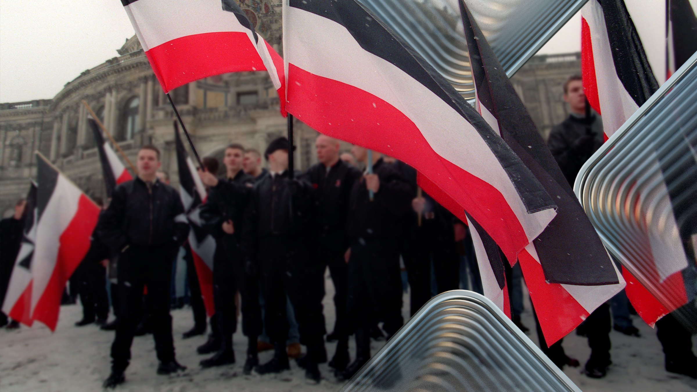 Schwarzgekleidete Menschen tragen Fahnen der NPD