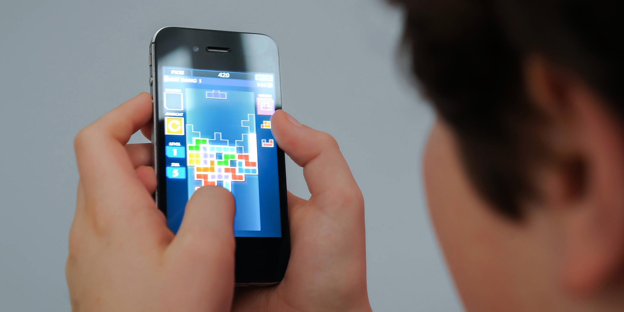 Ein Kind benutzt ein Smartphone und spielt das Spiel Tetris