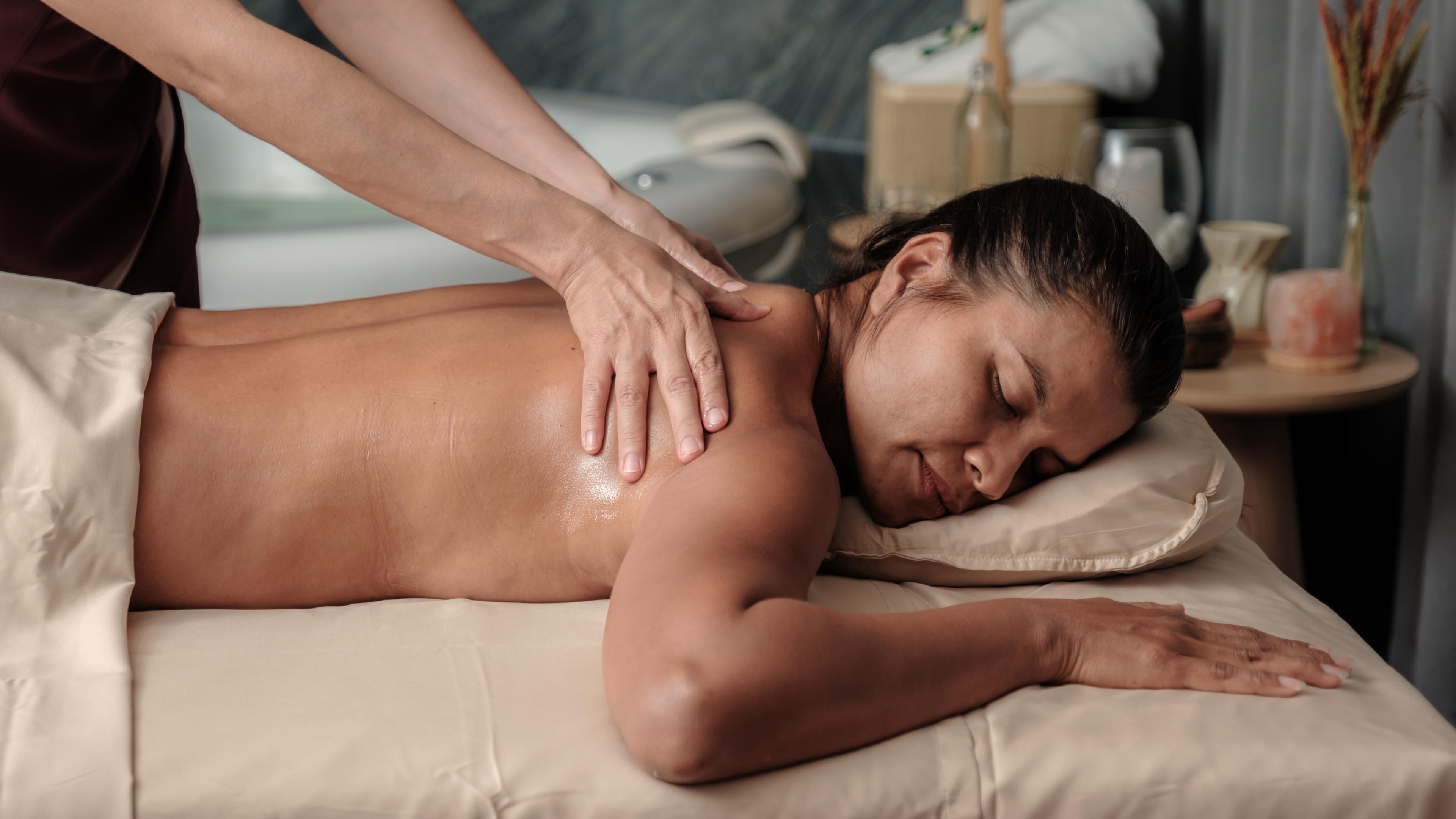 Ein Frau liegt auf einer Massage-Liege in einem Thai-Massage-Studio und bekommt eine Rückenmassage.