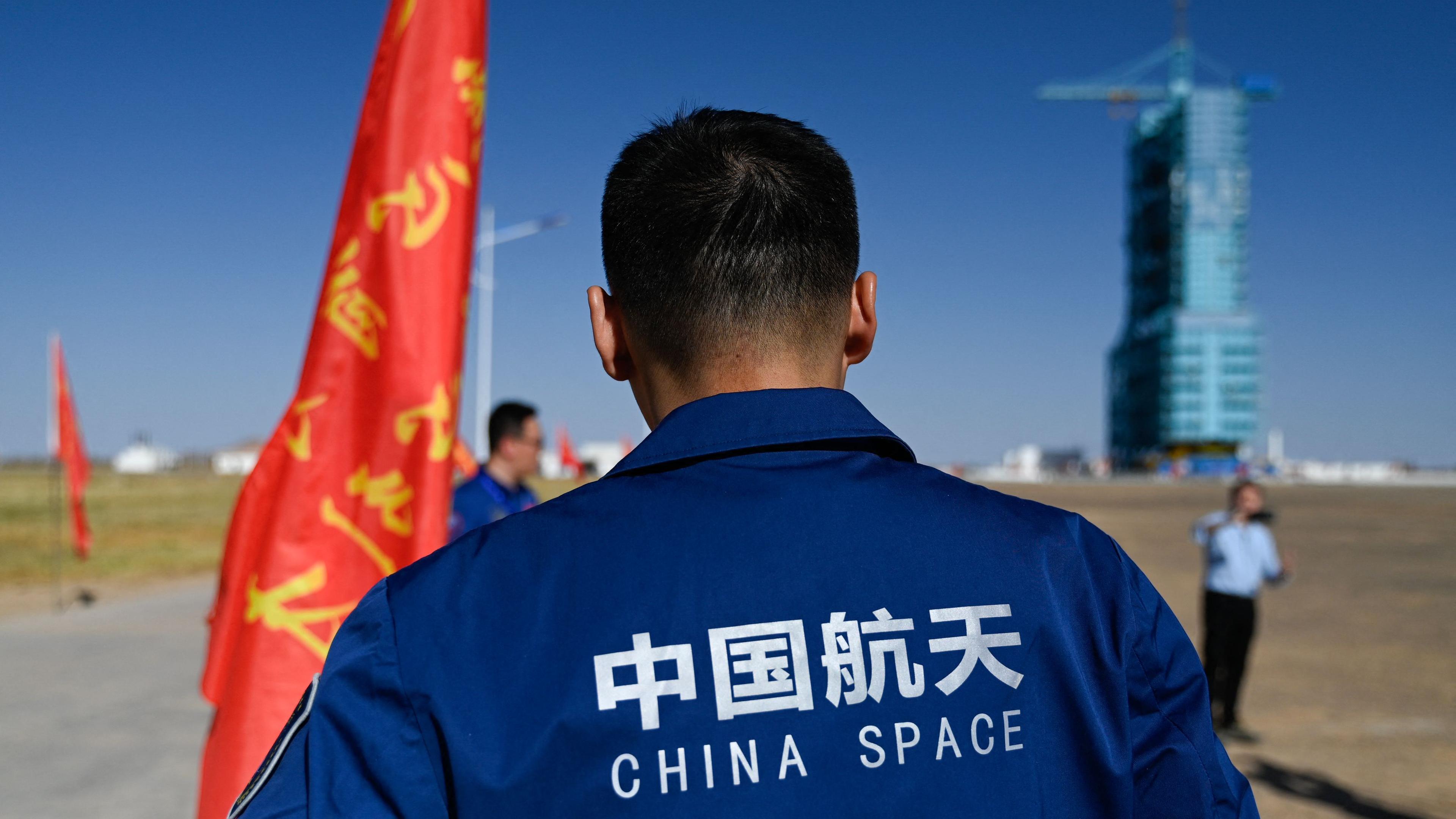 A staff member stands before a Long March-2F carrier rocket, carrying the Shenzhou-17 spacecraft, on the launch pad encased in a shield at the Jiuquan Satellite Launch Centre in the Gobi desert in northwest China on October 25, 2023