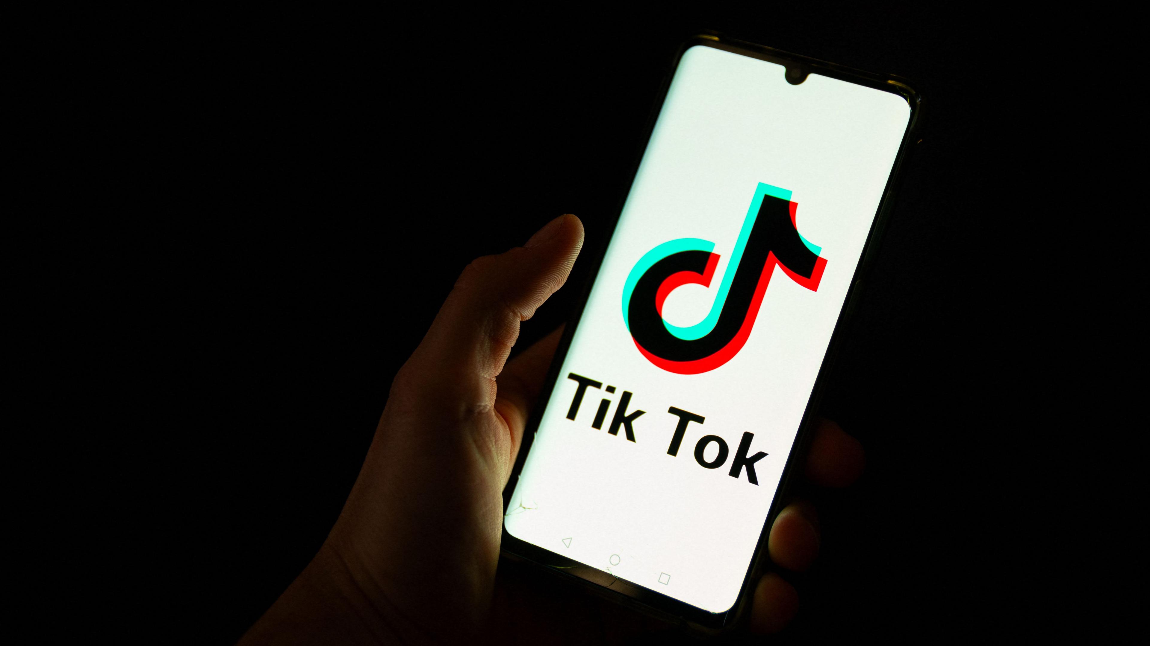 Eine Person hält ein Smartphone mit dem TikTok-Logo.