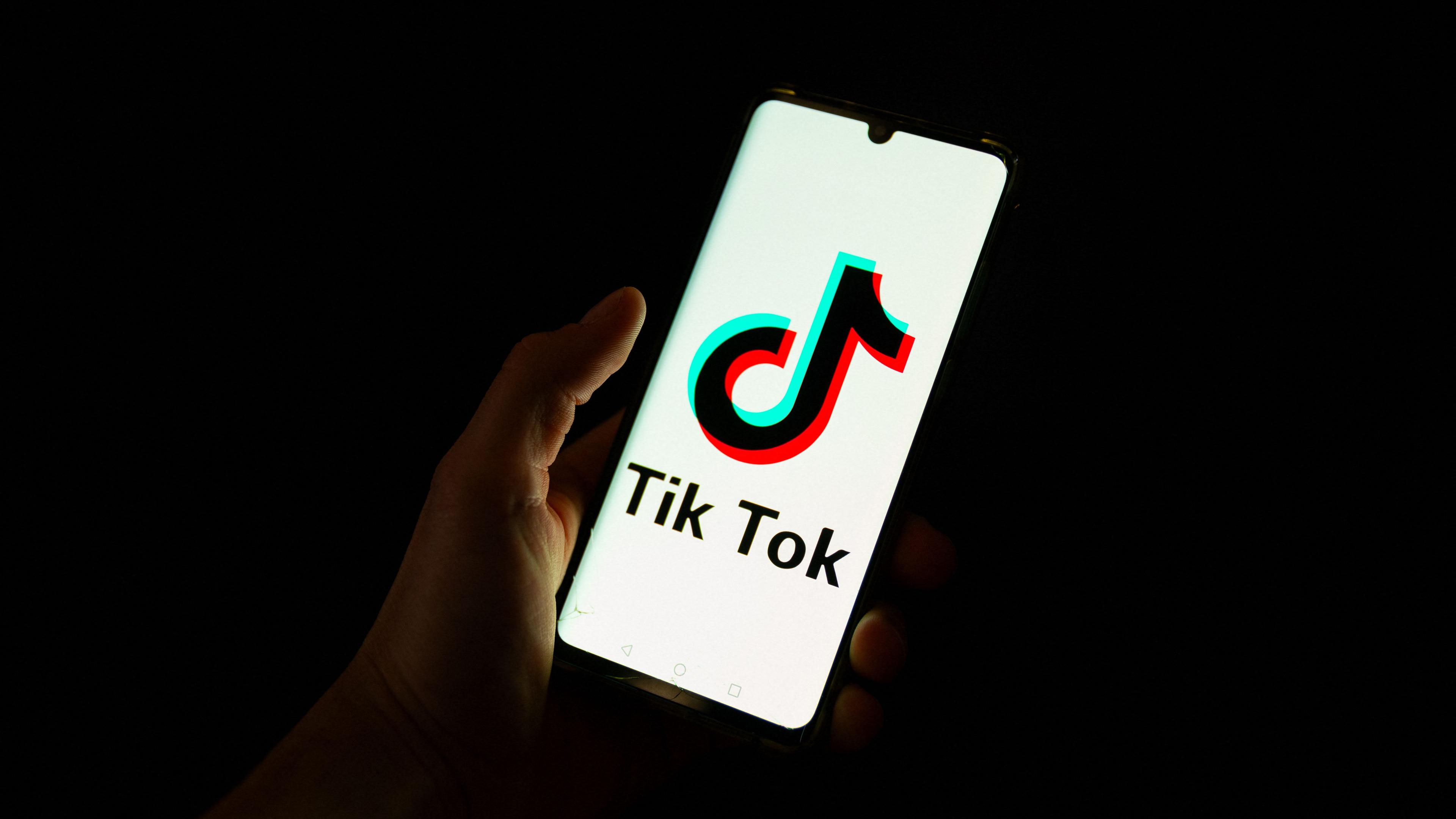 Dieses am 19. April 2024 aufgenommene Foto zeigt einen Mann, der in einem Büro in Paris ein Smartphone mit dem Logo der chinesischen Social-Media-Plattform Tiktok hält.