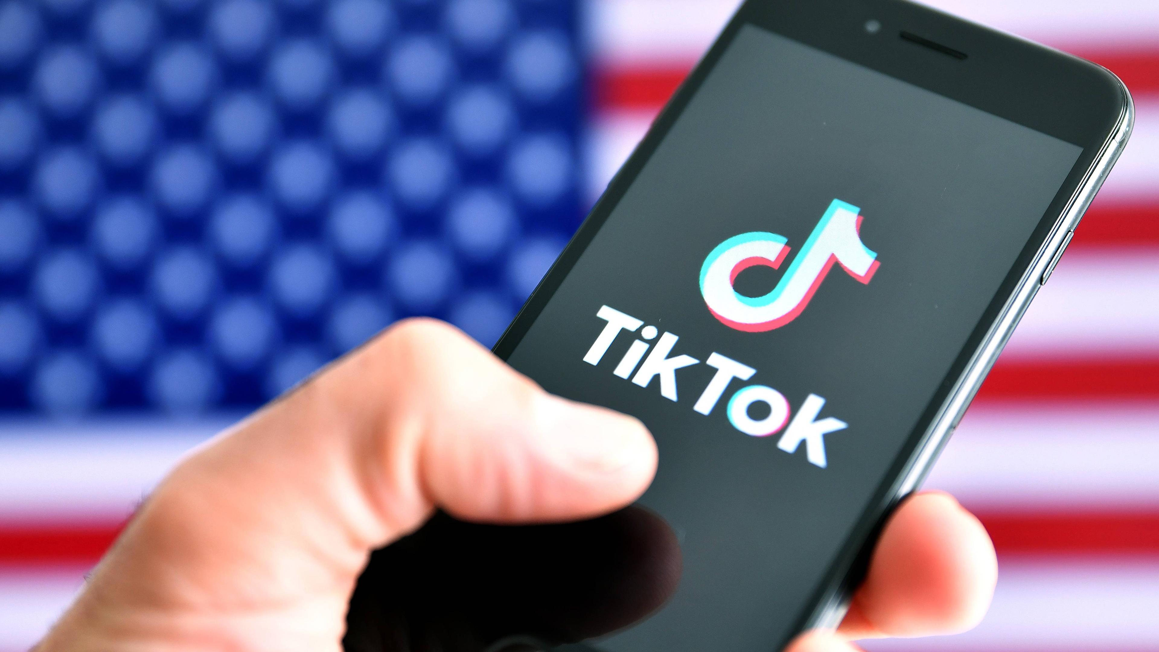 Symbolbild: TikTok-APP auf Smartphone vor USA-Flagge