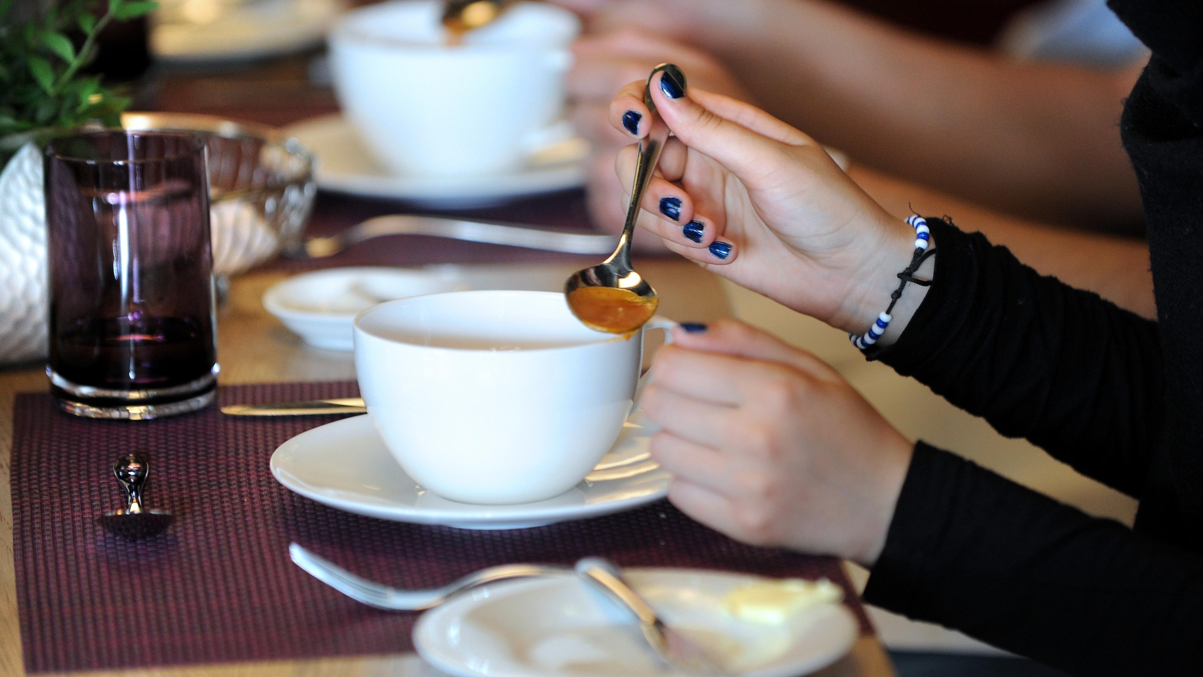 Schüler sitzen am gedeckten Tisch und essen Suppe.