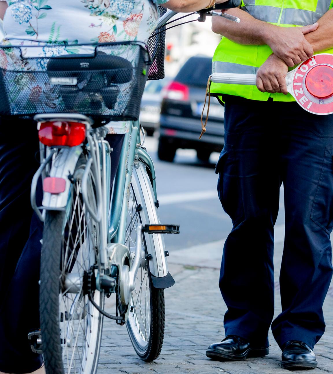 Ein Polizist kontrolliert eine Fahrradfahrerin.