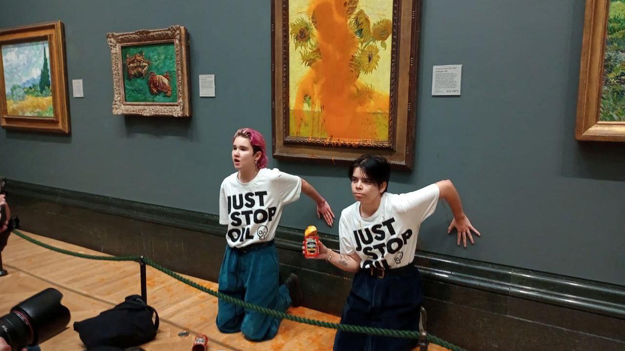 Activists of "Just Stop Oil" glue their hands to the wall after throwing soup at a van Gogh's painting "Sunflowers" at the National gallery in London