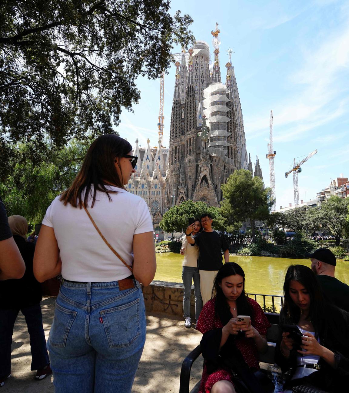 Archiv: Touristen fotografieren am 13. April 2024 mit der Basilika Sagrada Familia in Barcelona im Hintergrund.