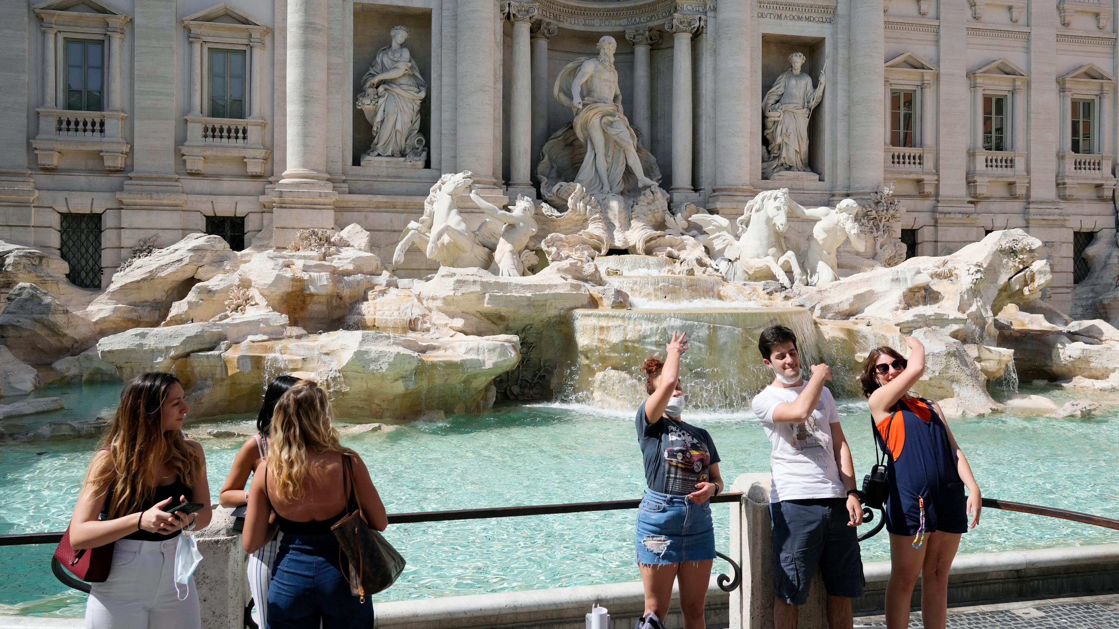 Touristen werfen Münzen in den Trevi-Brunnen in Rom 