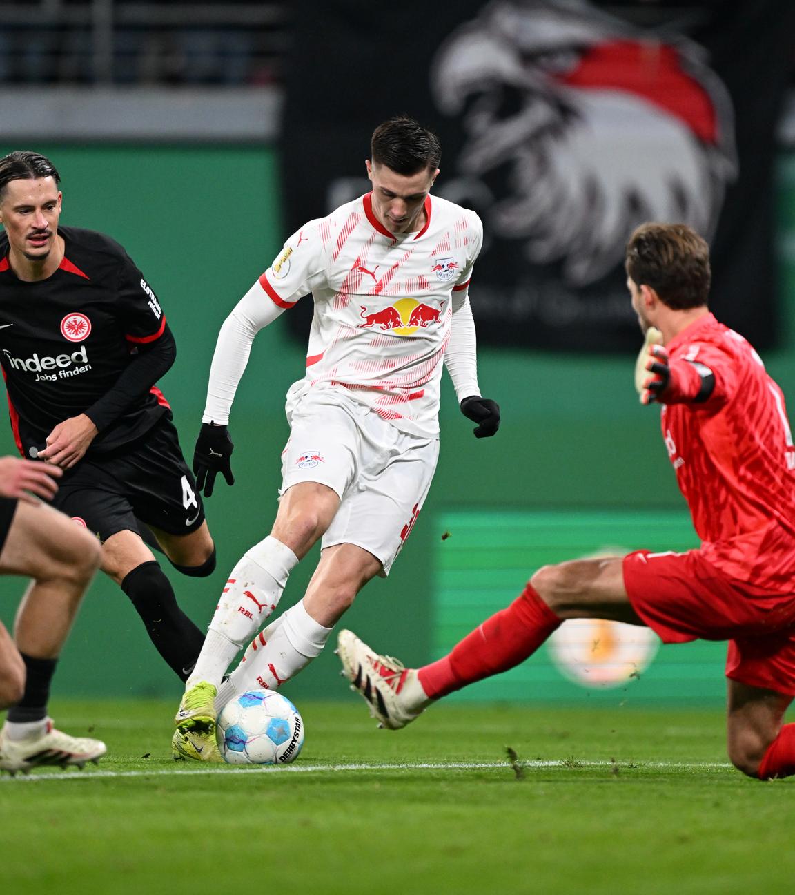 Leipzigs Benjamin Sesko (2.vr) und Frankfurts Torwart Kevin Trapp (r) in Aktion.