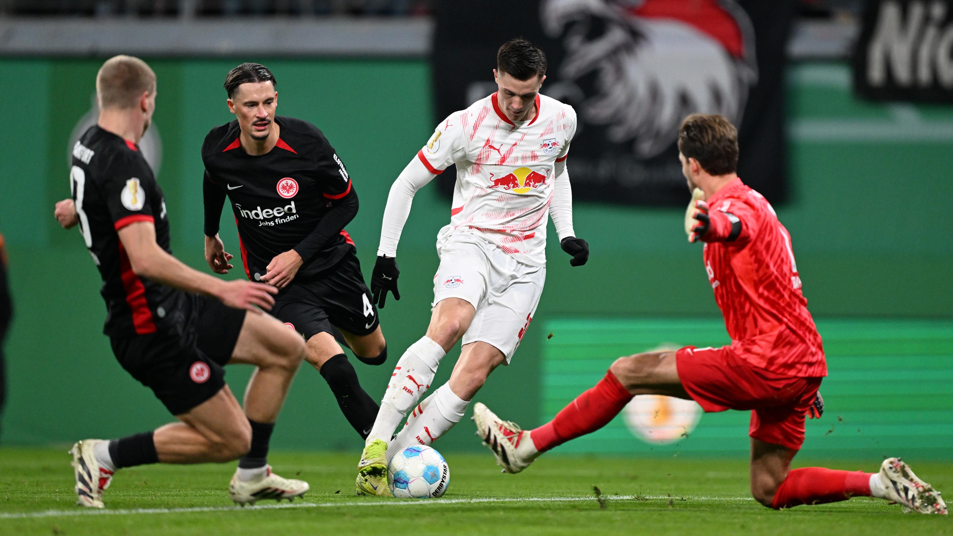 Leipzigs Benjamin Sesko (2.vr) und Frankfurts Torwart Kevin Trapp (r) in Aktion.