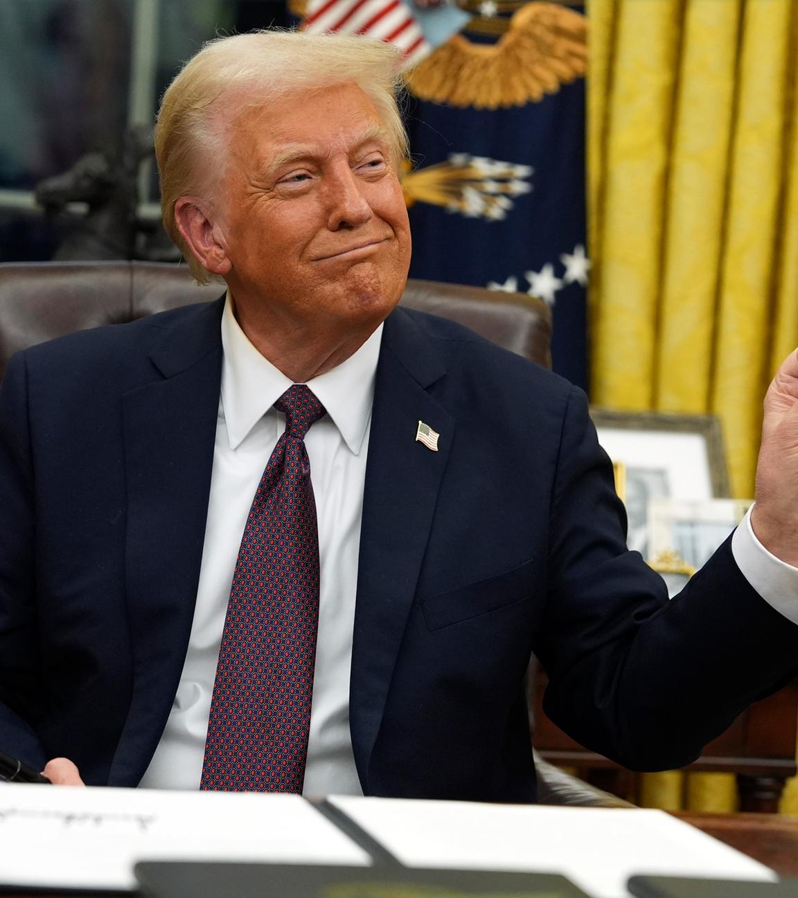 President Donald Trump holds up the letter that former President Joe Biden left for him in the desk as he signs executive orders in the Oval Office of the White House