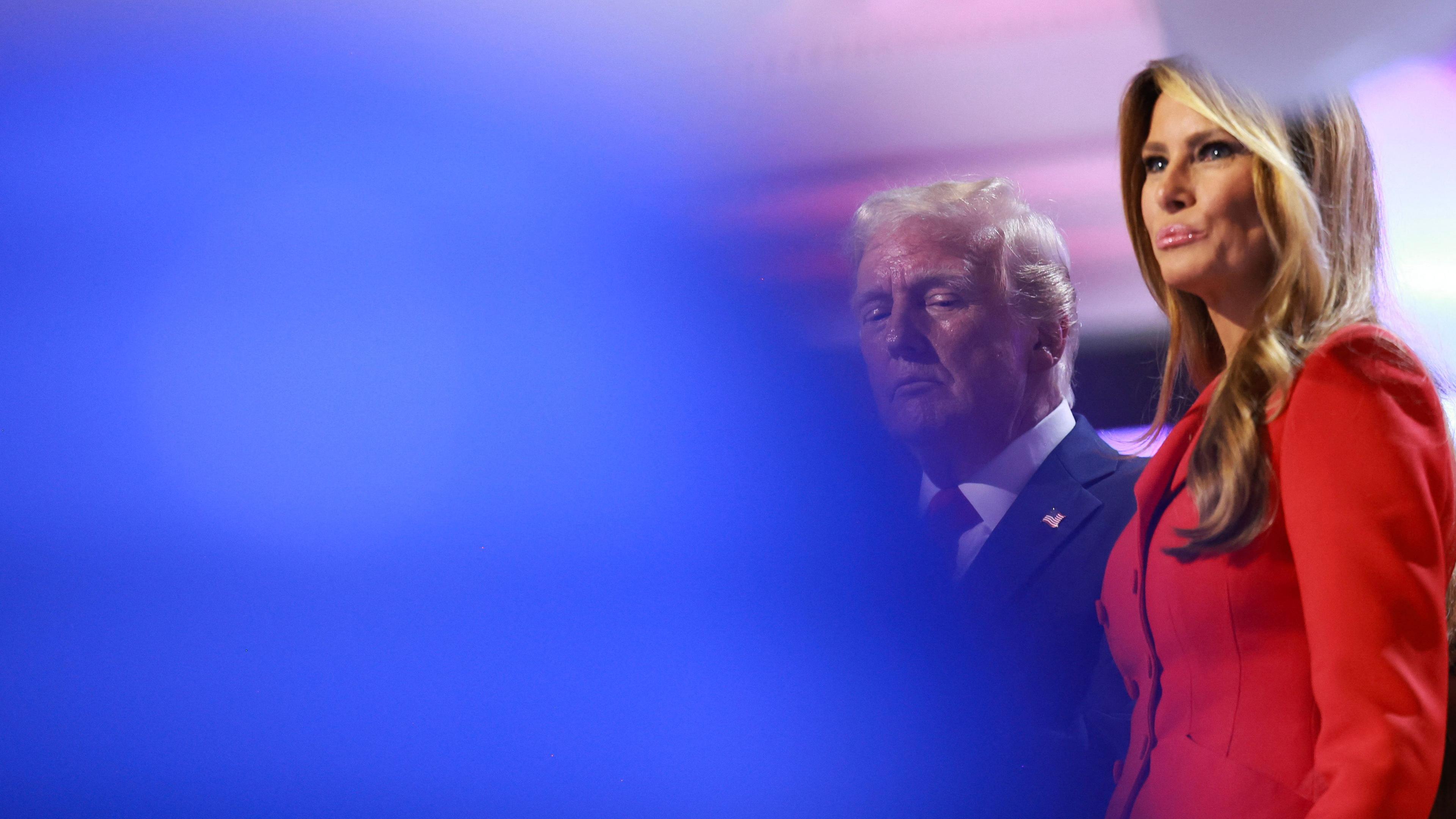 Die Gesichter von Melania Trump und Donald Trump auf der Bühne im Vordergrund ist eine große unscharfe blaue Fläche von einem fallenden Luftballon zu sehen.