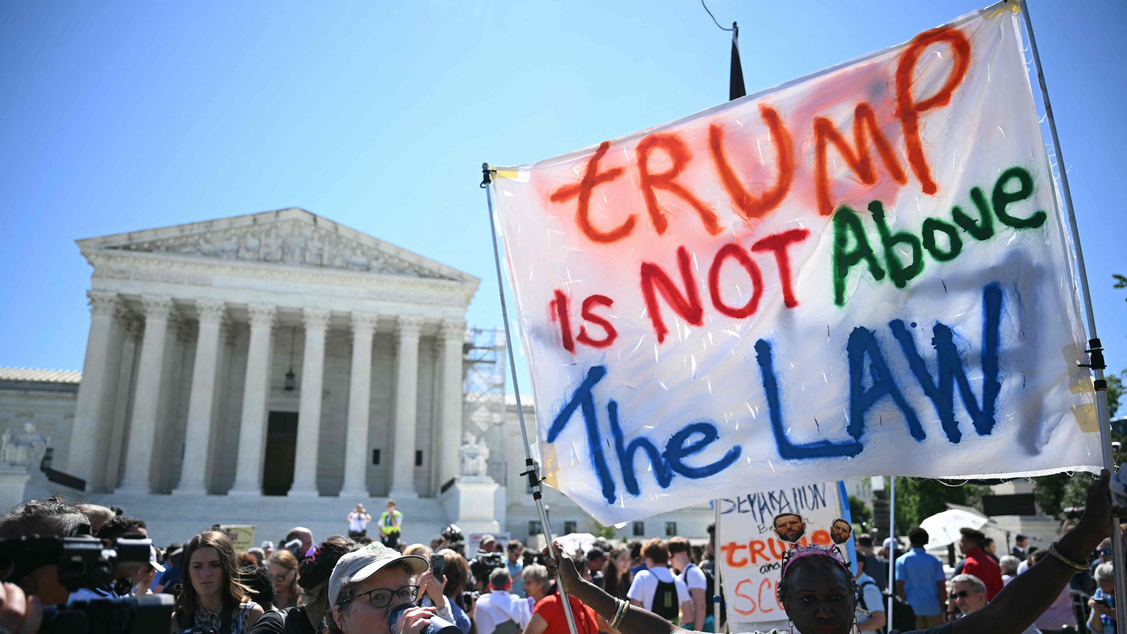 Demonstrant hält Transparent mit Aufschrift "Trump is not above the law" hoch