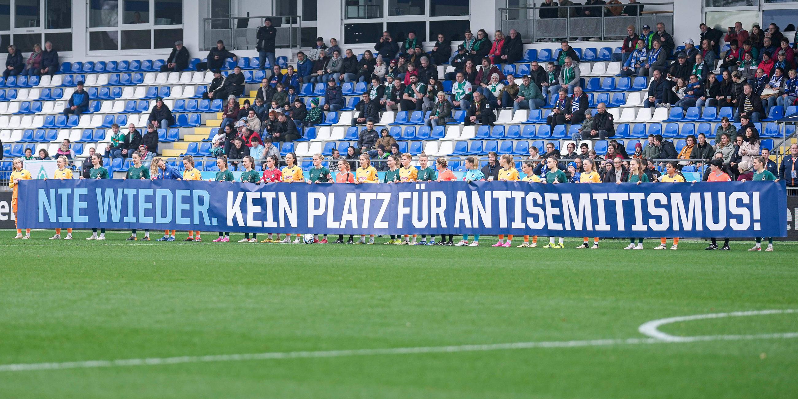 Spielerinnen von TSG 1899 Hoffenheim und SV Werder Bremen mit einem Banner vor dem Anpfiff: Spruchband mit der Aufschrift: Nie wieder. Kein Platz für Antisemitismus