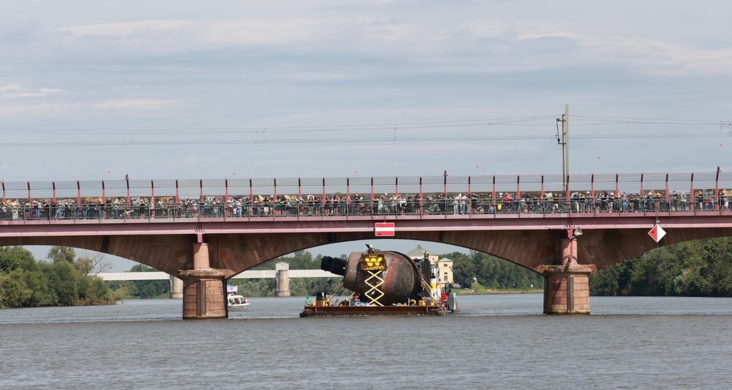 Das U-Boot fährt auf die Seite gedreht unter einer tiefen Brücke hindurch