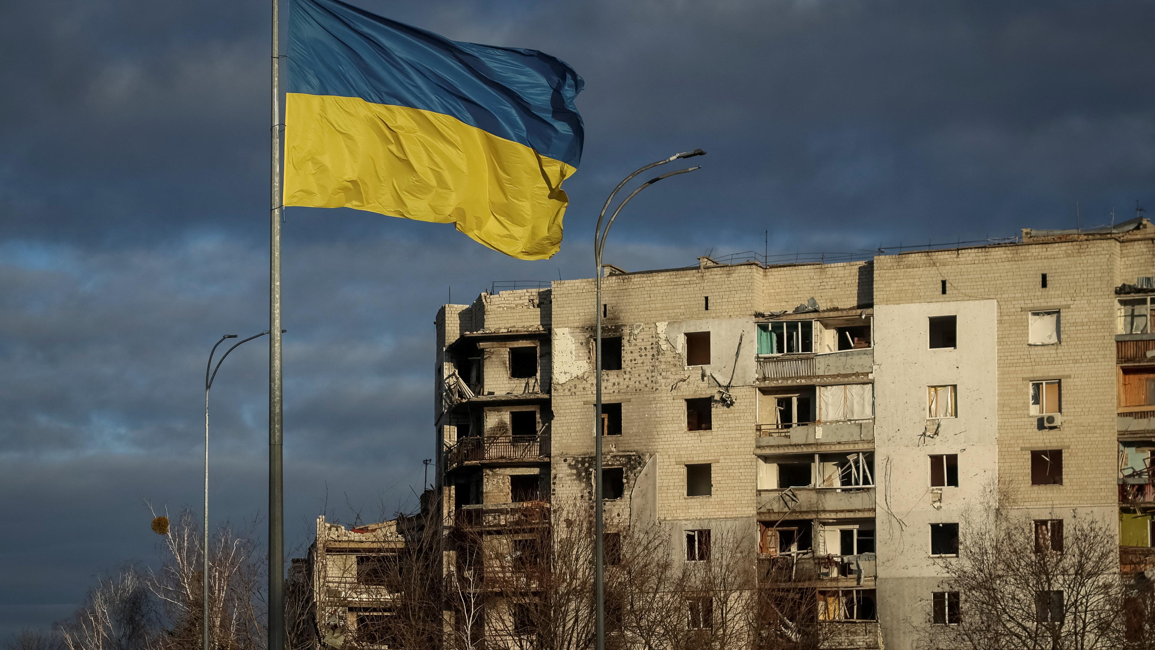 Die ukrainische Flagge weht vor einem zerstörten Haus in der Region Kiew