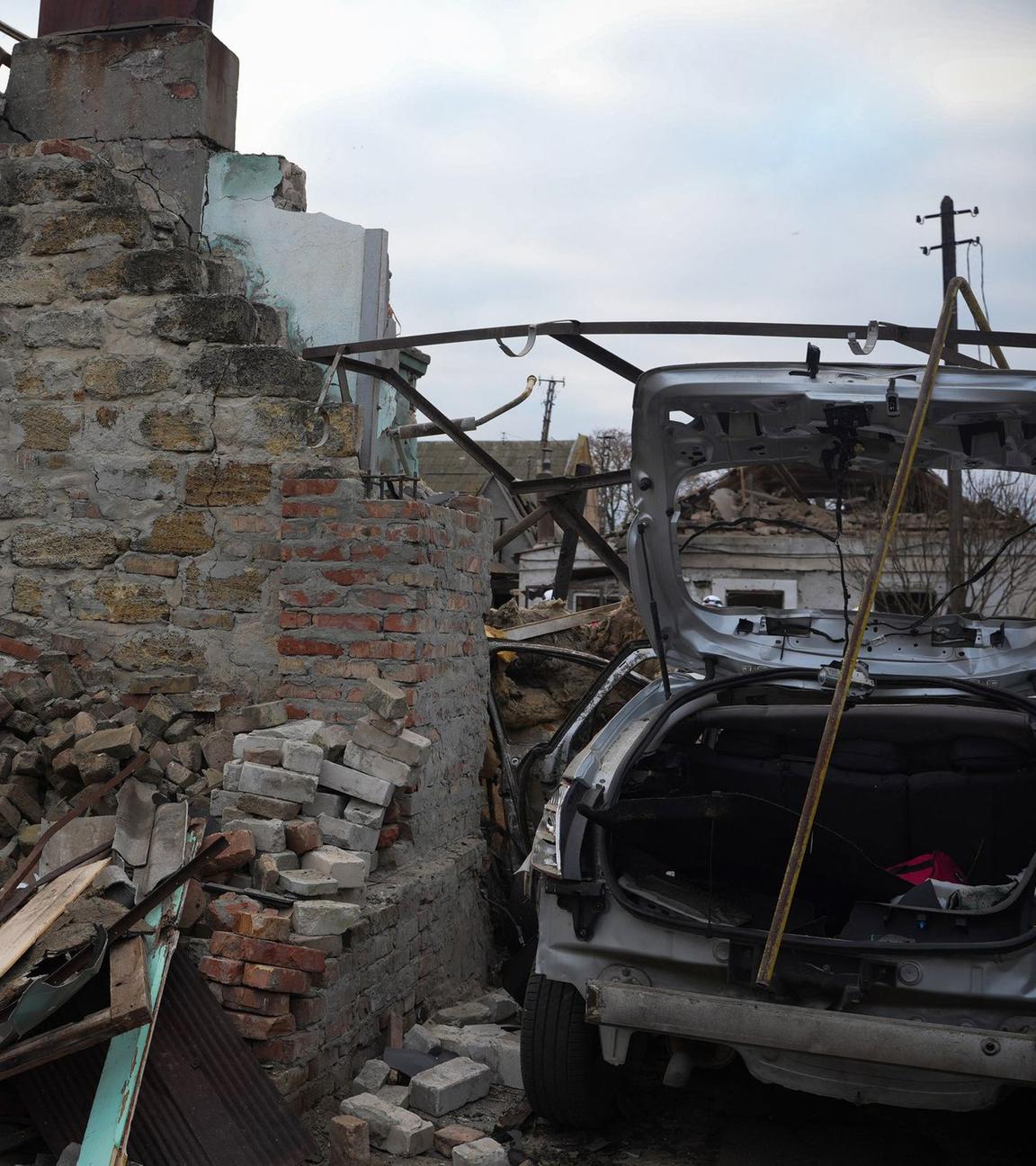 Zerstörtes Auto neben zerstörtem Gebäude im Kriegsgebiet in der Ukraine