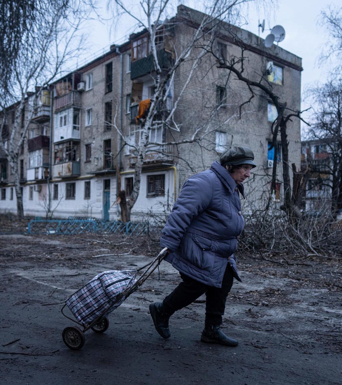 Ukraine, Kupjansk: Eine Einheimische geht zur Verteilungsstelle für humanitäre Hilfe vor einem Haus, das nach ukrainischen Angaben durch russischen Beschuss beschädigt wurde.