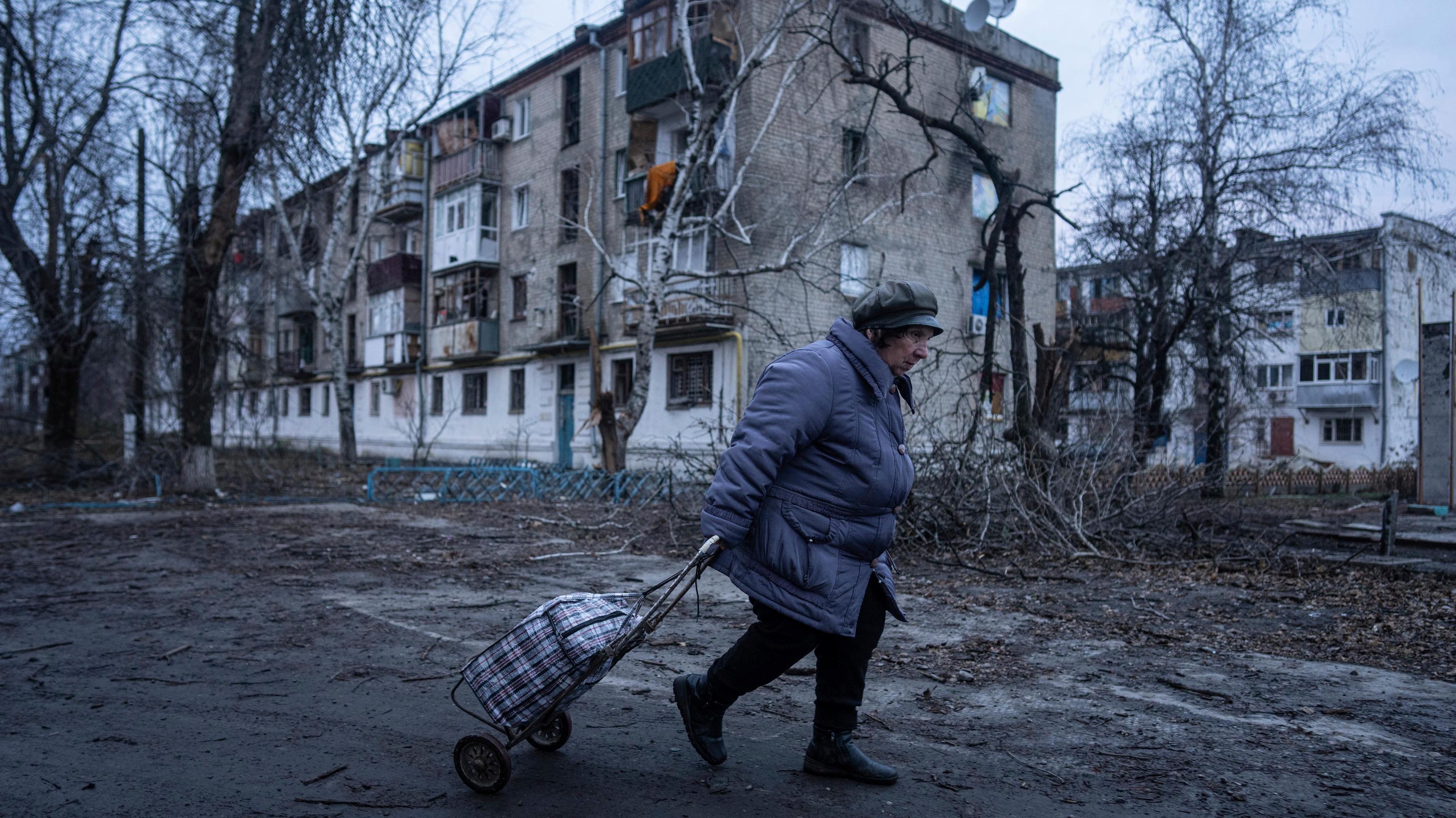 Ukraine, Kupjansk: Eine Einheimische geht zur Verteilungsstelle für humanitäre Hilfe vor einem Haus, das nach ukrainischen Angaben durch russischen Beschuss beschädigt wurde.