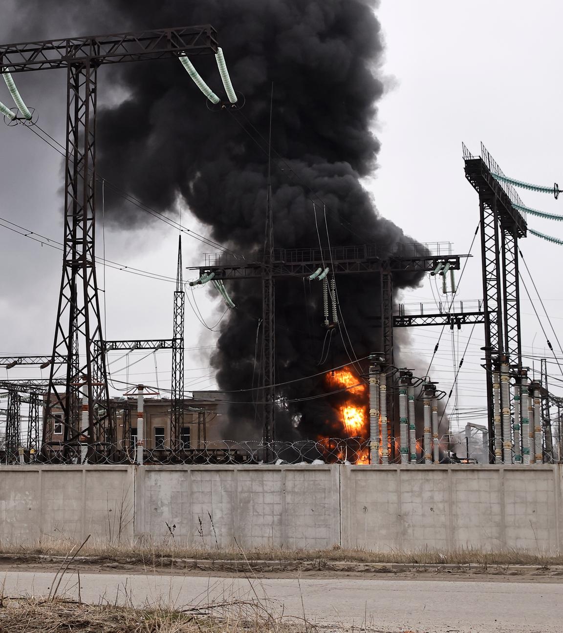 Ein Mann radelt nach einem russischen Angriff an einem Elektrizitätswerk vorbei. Dort ist ein Feuer ausgebrochen.