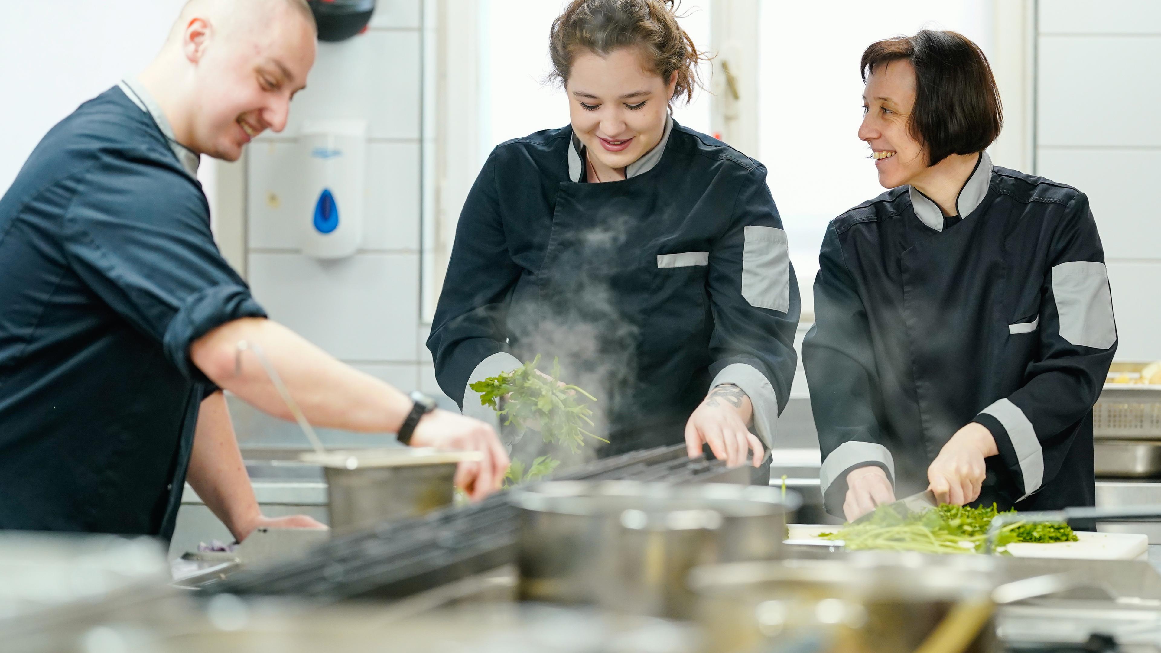 Rheinland-Pfalz, Deidesheim: Die aus der Ukraine stammenden Mitarbeiter Oleg (l-r), Antonia und Marina arbeiten in der Küche der Gaststätte Winzerverein.