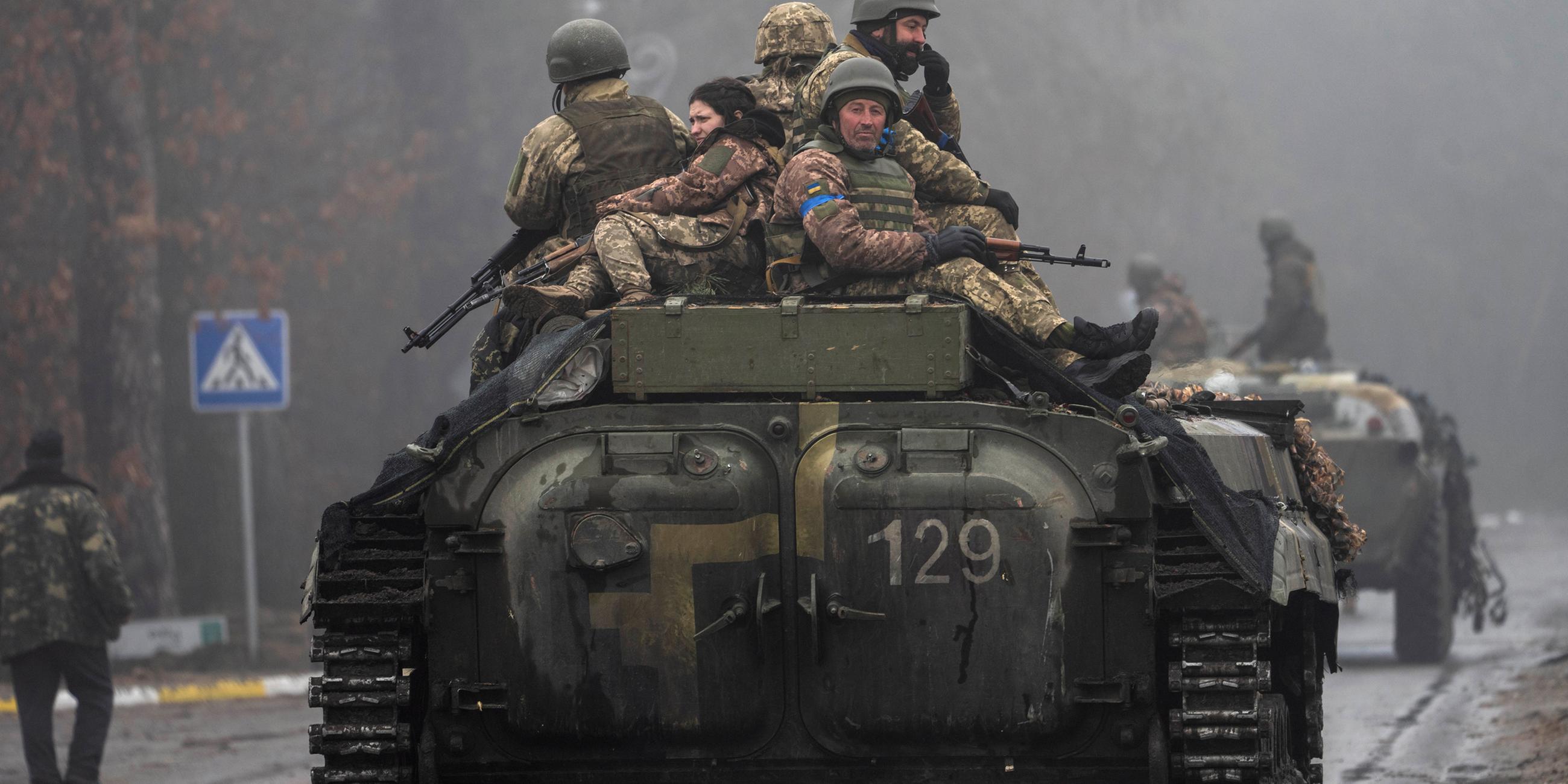 Ukrainische Soldaten sitzen auf einem fahrenden Militärfahrzeug