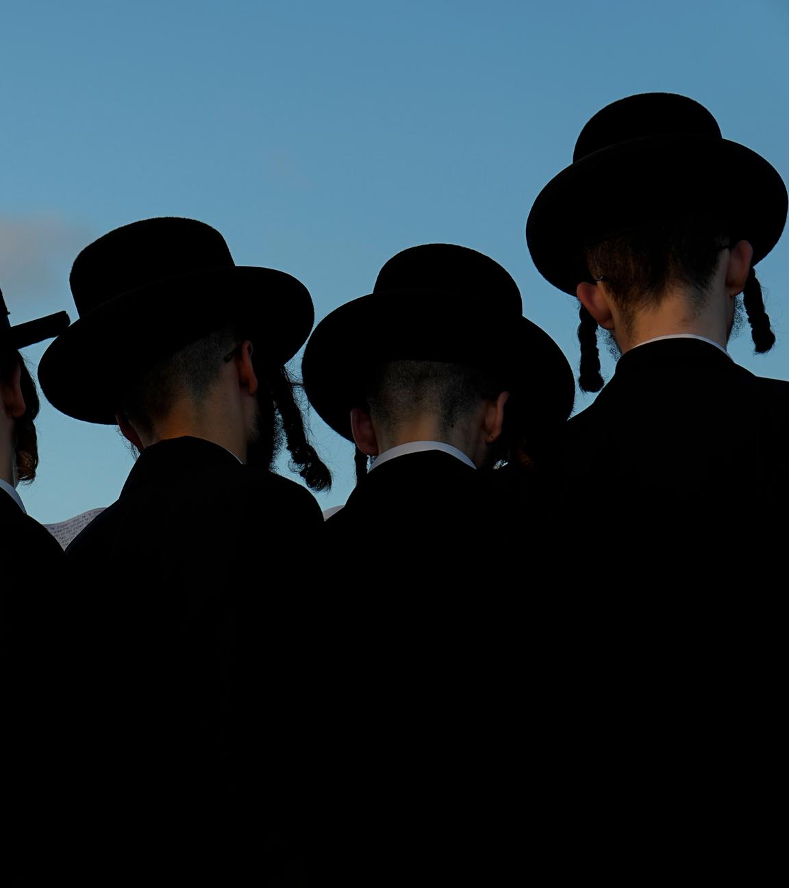 Ultraorthodoxe jüdische Männer beten auf einem Hügel mit Blick auf das Mittelmeer, während sie an einer Zeremonie teilnehmen. 