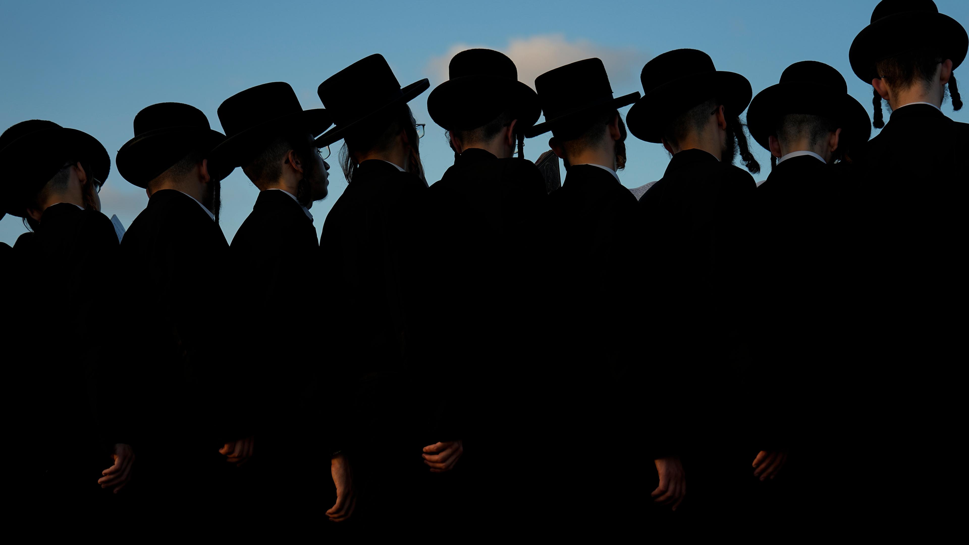 Ultraorthodoxe jüdische Männer beten auf einem Hügel mit Blick auf das Mittelmeer, während sie an einer Zeremonie teilnehmen. 